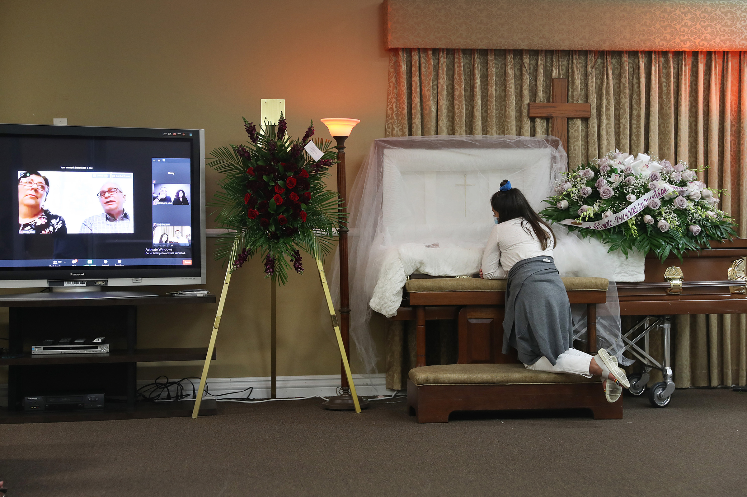 Asare Amaya, 10, mourns for her father, German Amaya, as family and friends are shown via a Zoom broadcast at the Maspons Funeral Home in Miami on Aug. 8, 2020. German Amaya, who died from COVID-19, had worked for 11 years at the Fontainebleau Miami Beach luxury hotel before he was furloughed in March. In late June, the family says, the hotel cut health care coverage for workers who had been laid off during the pandemic; in turn, the family lost his $10,000 death benefit. (Joe Raedle—Getty Images)