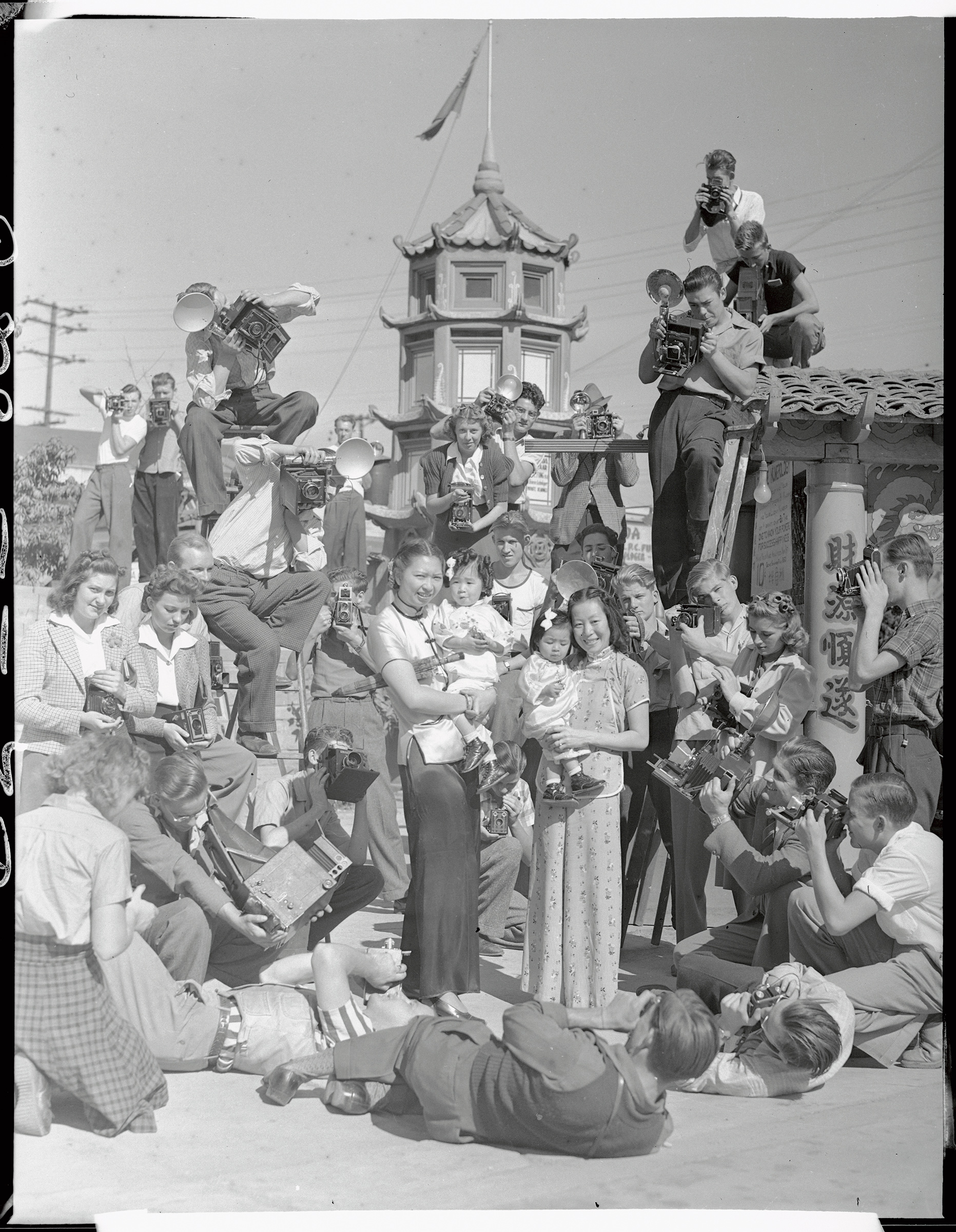 A mob of photographers descended upon China City, Los Angeles, when they heard that a prize contest is under way for the best amateur snaps of its people and its colorful nooks and corners. Pictured is a mob of candid camera fans shooting Mrs. Dorothy Siu (CQ) and Mrs. Chung Dat Loo as they hold little Gwendolyn Loo and Evelyn Loo on Oct. 1939 (Bettmann Archive/Getty Images)
