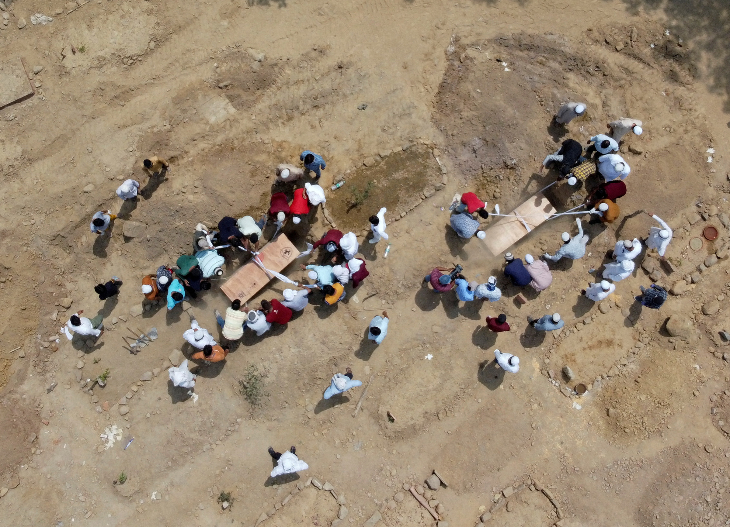 People bury the bodies of COVID-19 victims at a graveyard in New Delhi on April 16, 2021.