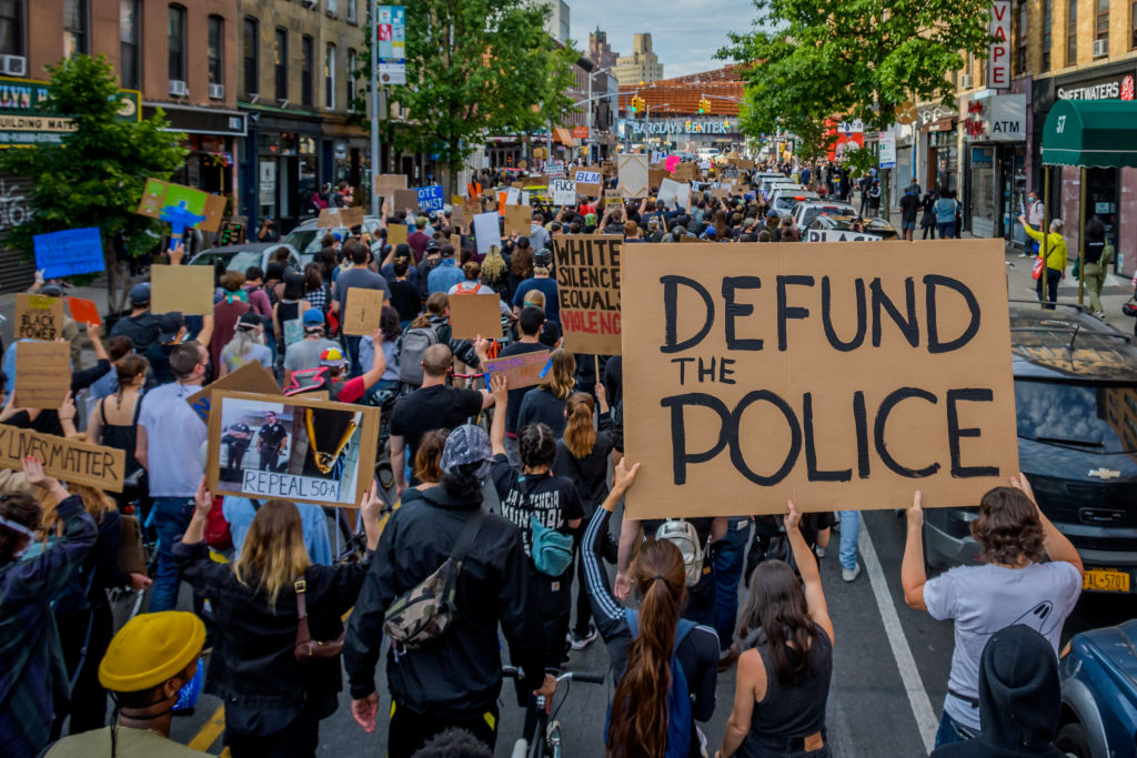 A participant holding a Defund The Police sign at the