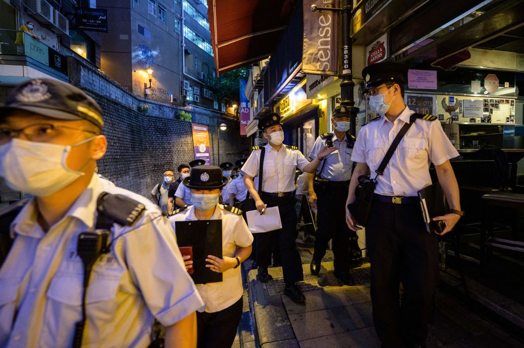 Food and Environmental Hygiene Department officers and police walk past restaurants and bars after they reopened, in Lan Kwai Fong, a popular drinking area in Hong Kong on April 29, 2021. (Anthony Wallace—AFP/Getty Images)
