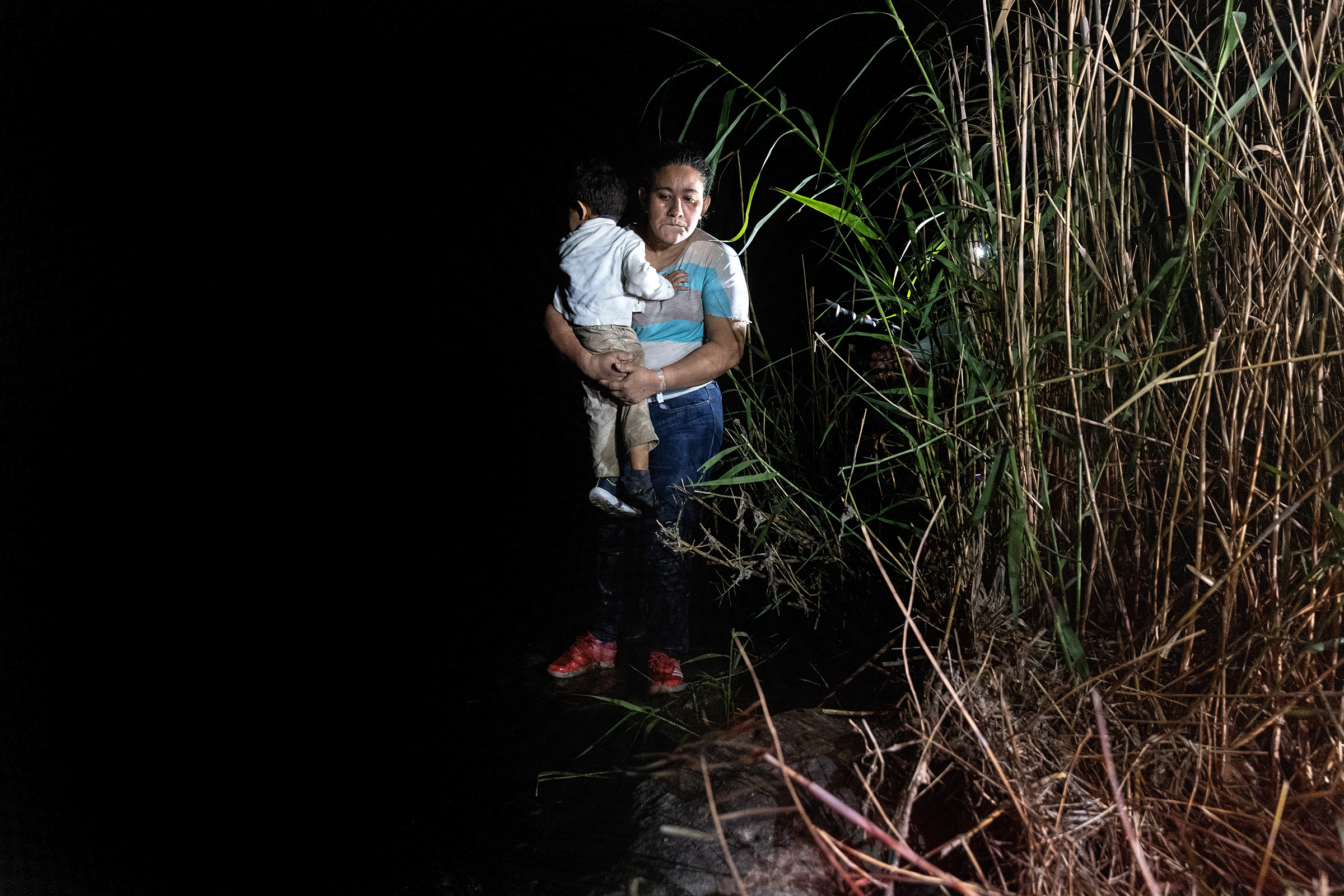 A mother holds her son on the bank of the Rio Grande in Roma, Texas, after being smuggled across the U.S.-Mexico border on April 14, 2021.