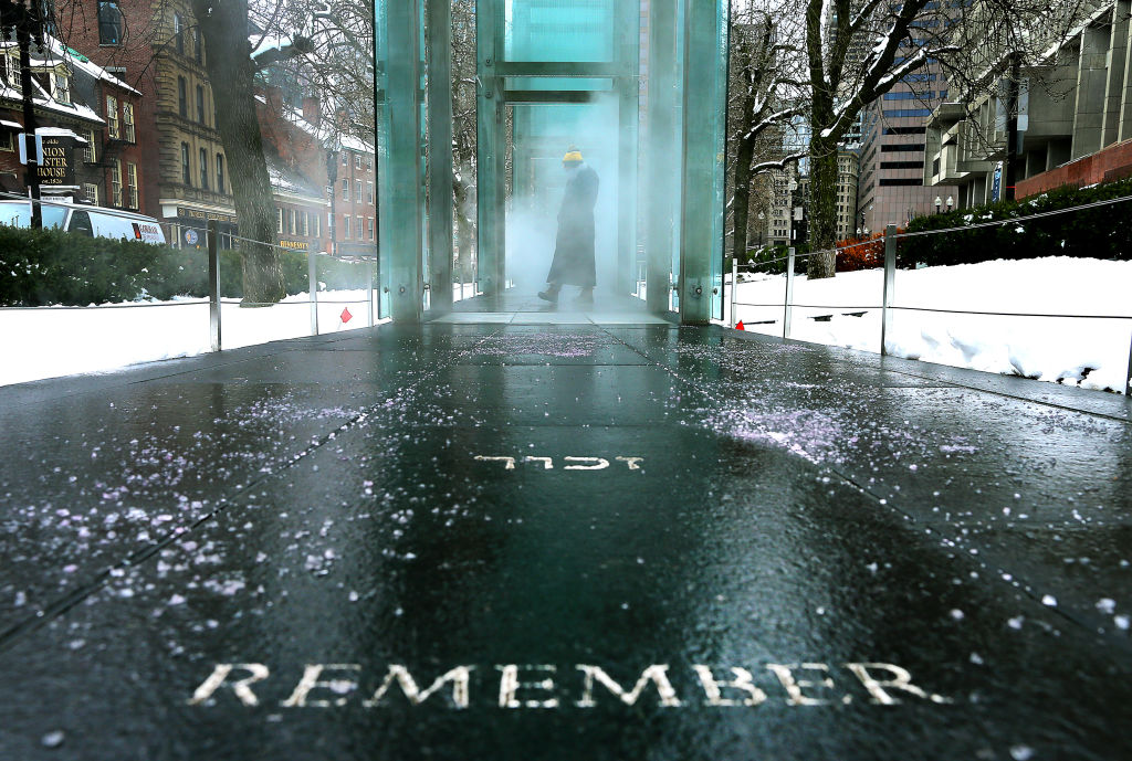 A person pauses to look at the inscriptions, representing the six million Jews killed in the Holocaust, inside the glass walls at the New England Holocaust Memorial in Boston on Jan. 27, 2021 (John Tlumacki—Boston Globe via Getty Images)