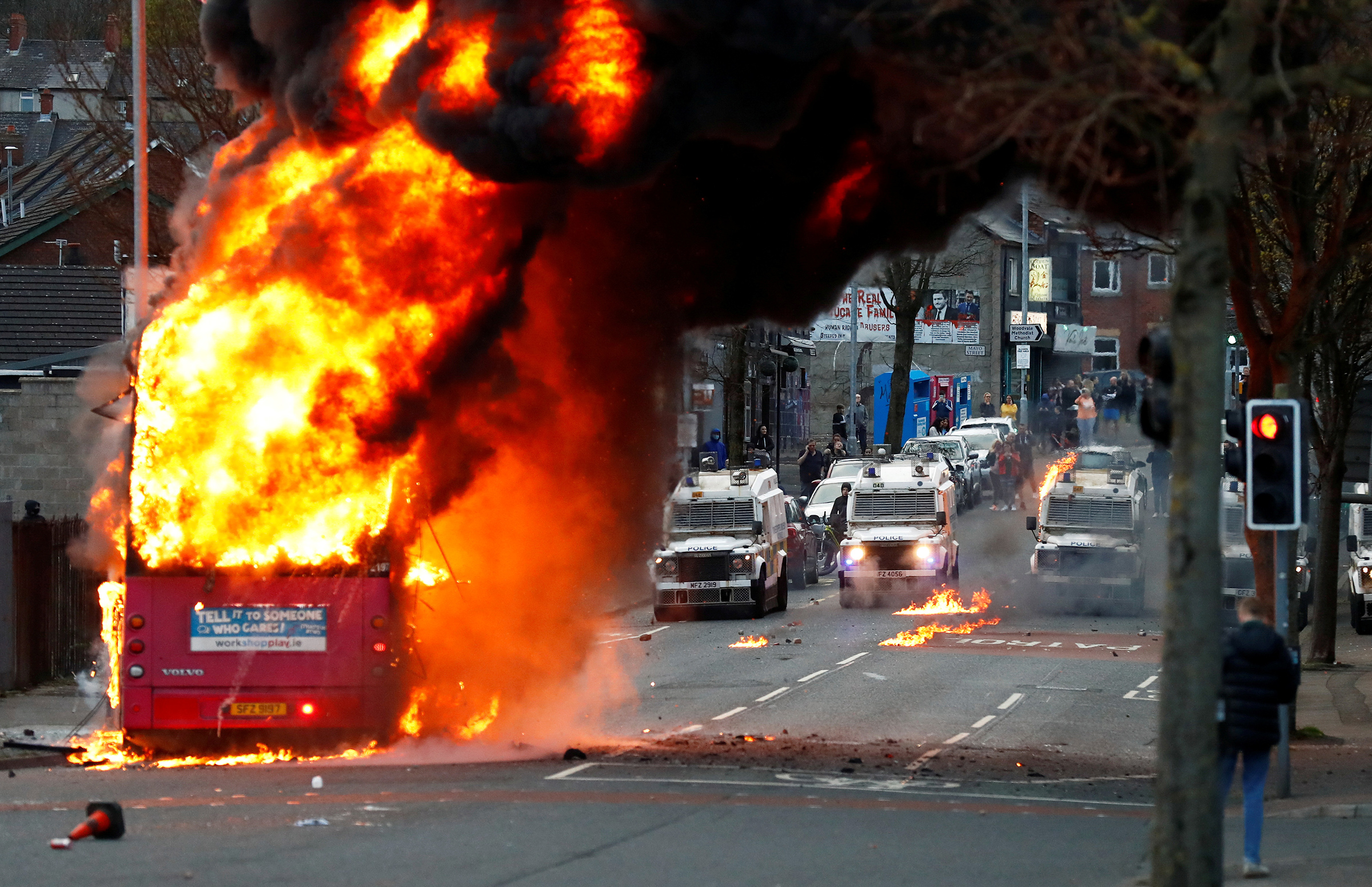 Police vehicles are seen behind a hijacked bus burns on the Shankill Road as protests continue in Belfast, Northern Ireland, April 7. (Jason Cairnduff—Reuters)