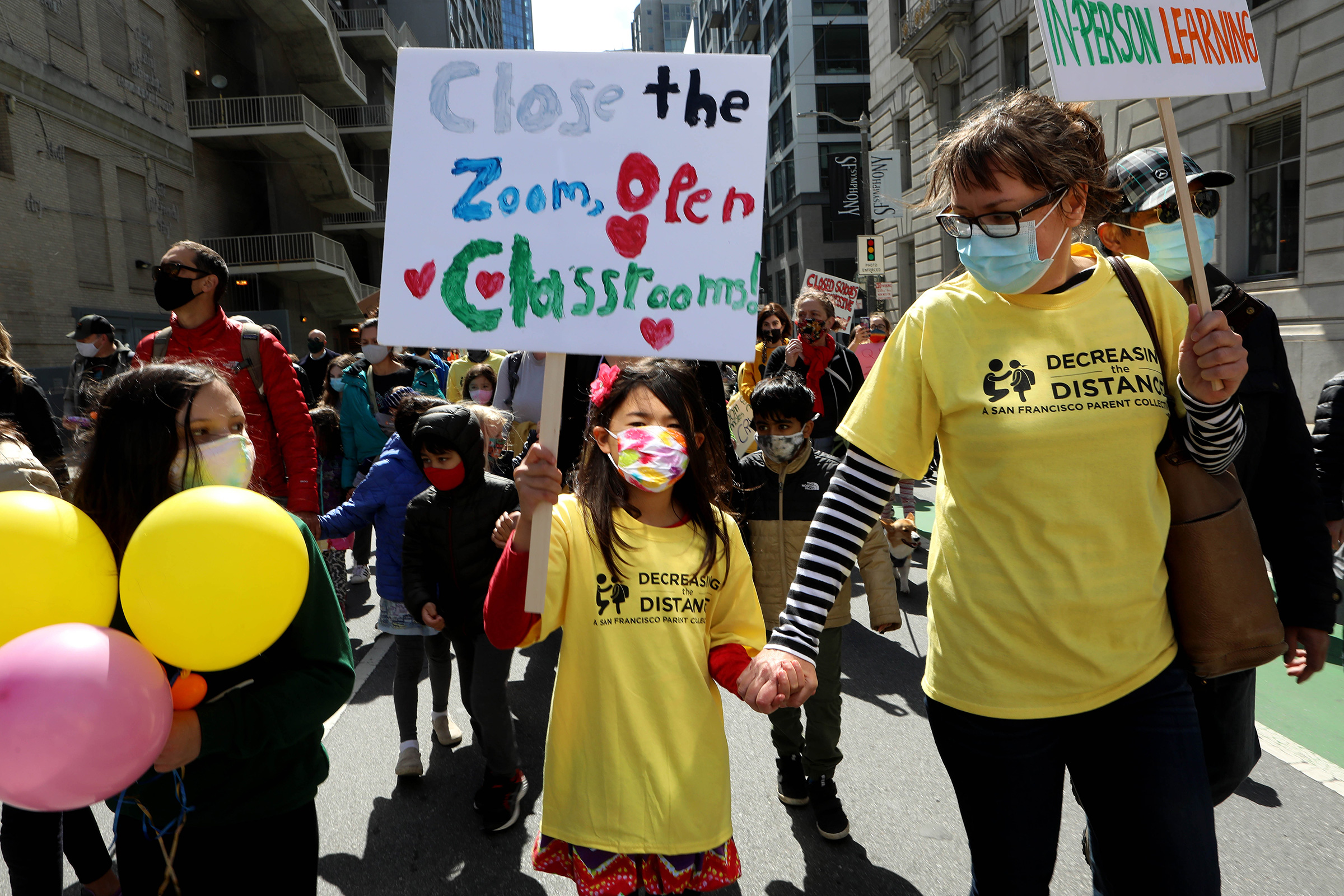 Kristina Leng, 9, marches to the Civic Center with her mother Monika Leng, and father Rodney Leng during the Families Rally to Demand Schools Fully Reopen event  in San Francisco, on March 13, 2021. (Yalonda M. James—The San Francisco Chronicle/Getty Images)