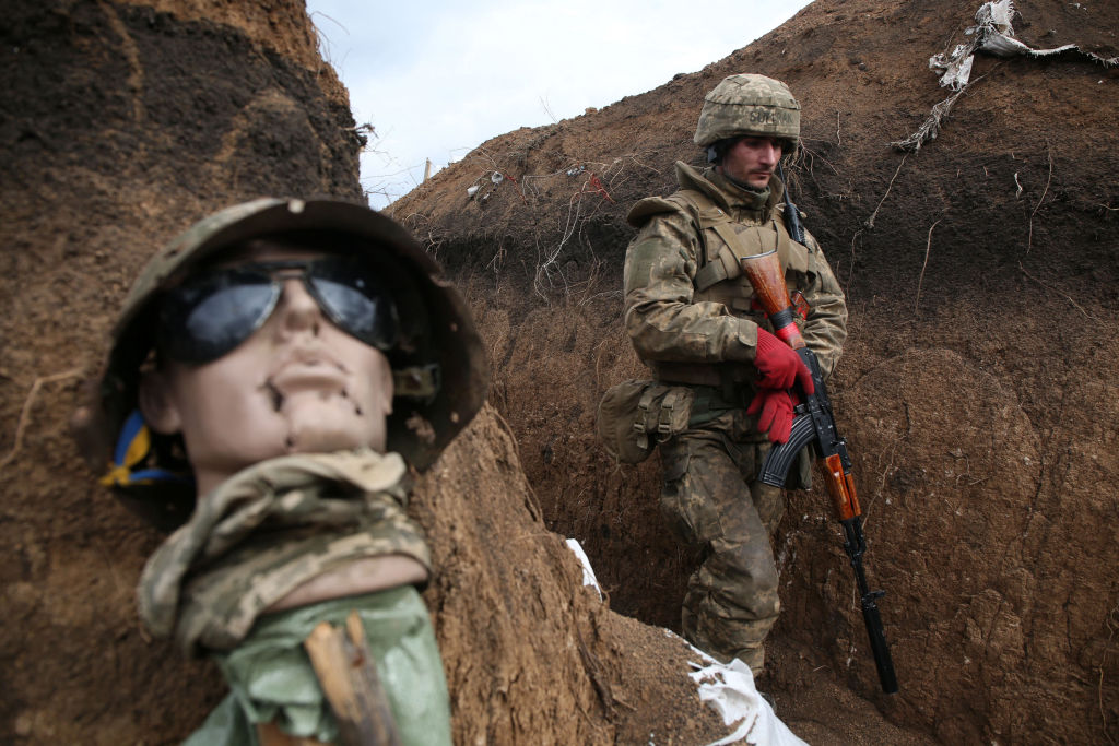 An Ukrainian serviceman walks in a trench by a sort of mannequin as he stands at his post on the frontline with Russia backed separatists near the town of Zolote, in the Lugansk region on April 8, 2021. - Ukrainian President Volodymyr Zelensky was travelling to the country's eastern frontline on April 8, 2021, after a surge in clashes with separatist forces and a spike in tensions with Moscow. Fighting between the Ukrainian army and separatists has intensified in recent weeks, raising fears of a major escalation in the long-running conflict over the mainly Russian-speaking Donbas region. (Photo by STR / AFP) (Photo by STR/AFP via Getty Images) (AFP via Getty Images)
