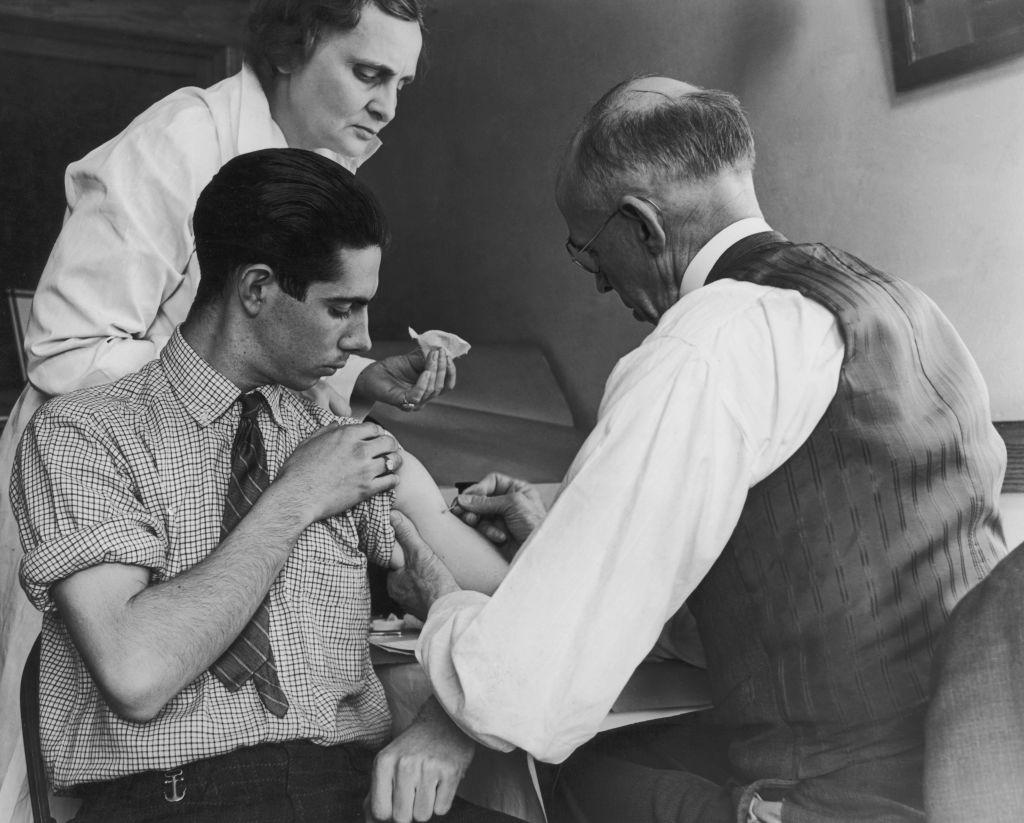 A teenage boy is vaccinated against smallpox by a school doctor and a county health nurse, Gasport, N.Y., March 15, 1938. (Harry Chamberlain—FPG/Hulton Archive/Getty Images)
