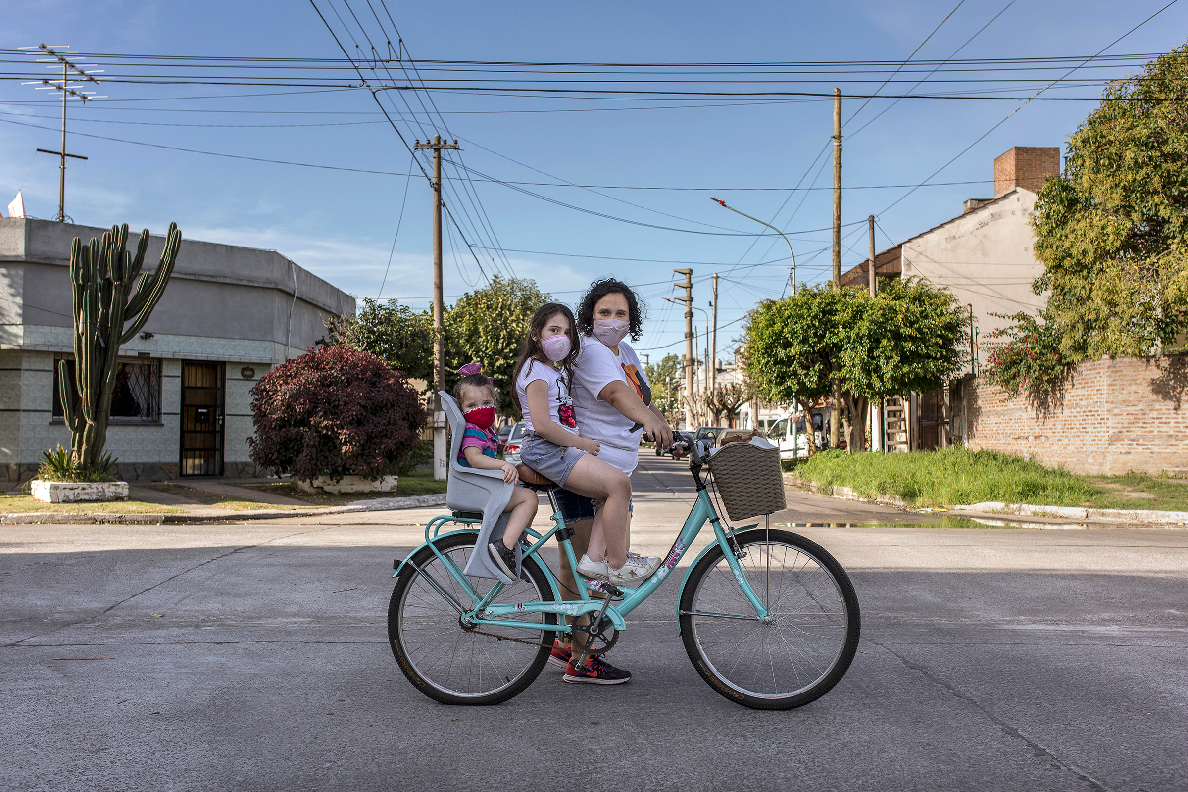 María Teresa Arzamendia stands for a portrait with her two daughters Leia and Catalina and her bicycle with pastries in El Palomar, Buenos Aires Province, on April 17. (Sarah Pabst for TIME)