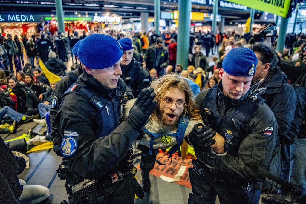 Royal Dutch police officers escort a Greenpeace activist during a protest to denounce airline pollution in the main hall of the Amsterdam Schiphol airport on December 14, 2019. (Robin Utrecht – ANP/AFP/Getty Images)
