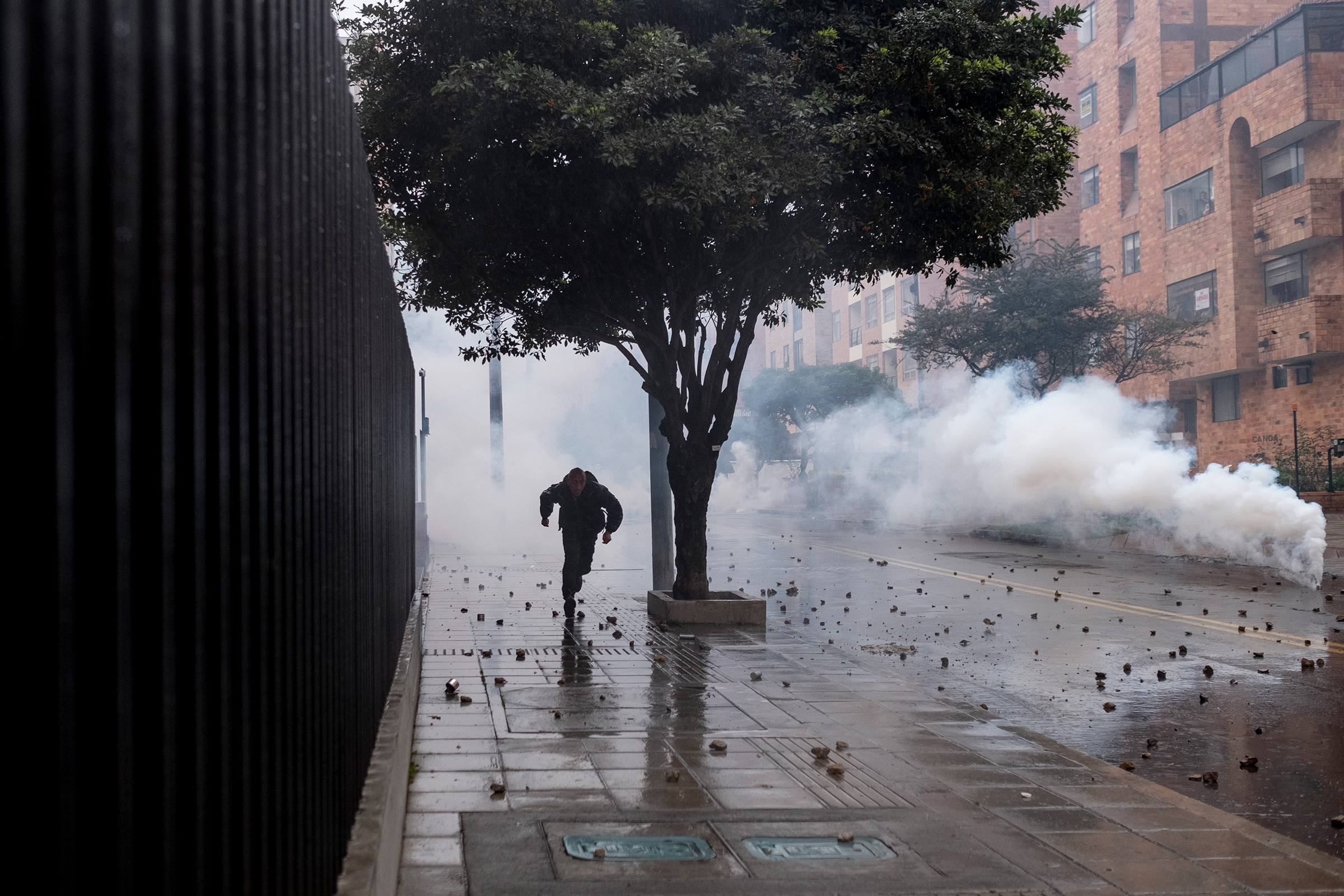A protester flees tear gas used by the police in northern Bogotá on May 1. (Santiago Mesa—Reojo Colectivo)
