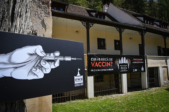 A banner reading "Who's afraid of the vaccine?" in Romanian and depicting syringes as vampire fangs advertises the vaccination marathon organized at "Bran Castle" in Bran village in the central Transylvania region of Romania on May 8, 2021.