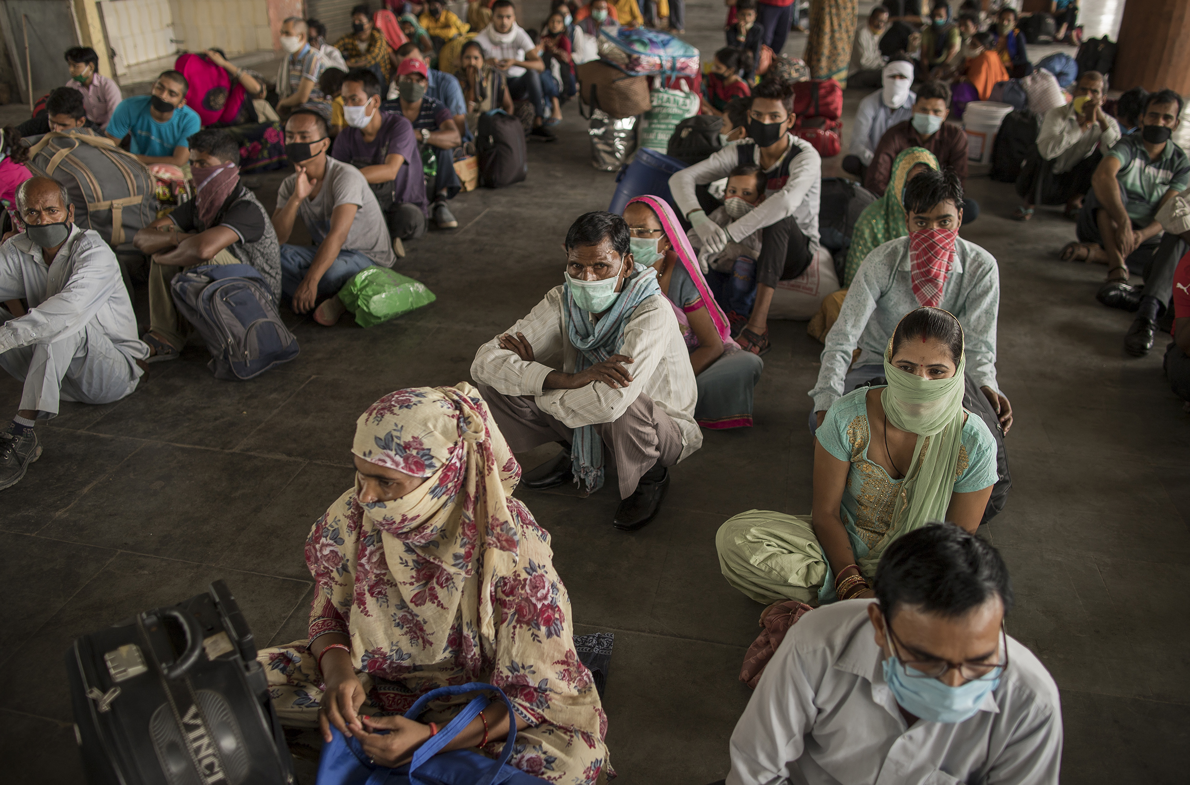 Migrant workers sit at a bus terminal as they wait to catch state-provided transportation to their home villages, in Greater Noida, Uttar Pradesh, on May 29, 2020. Migrant workers, who form part of India's vast informal sector, were the worst hit by the shutdown. Millions lost jobs and incomes. (Anindito Mukherjee—Bloomberg/Getty Images)