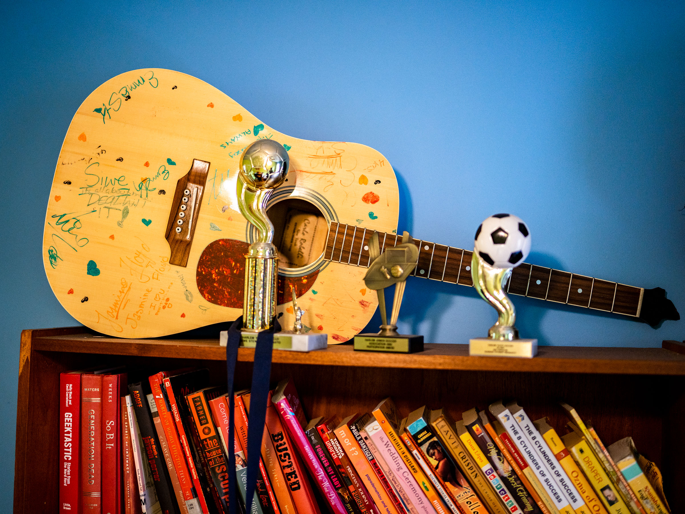 A guitar amongst trophies and books on a shelf in Siwe's bedroom. “She was brilliant," her mother said. "She was beautiful. She was a writer. She was a guitar player. She was a dancer." (Elias Williams for TIME)
