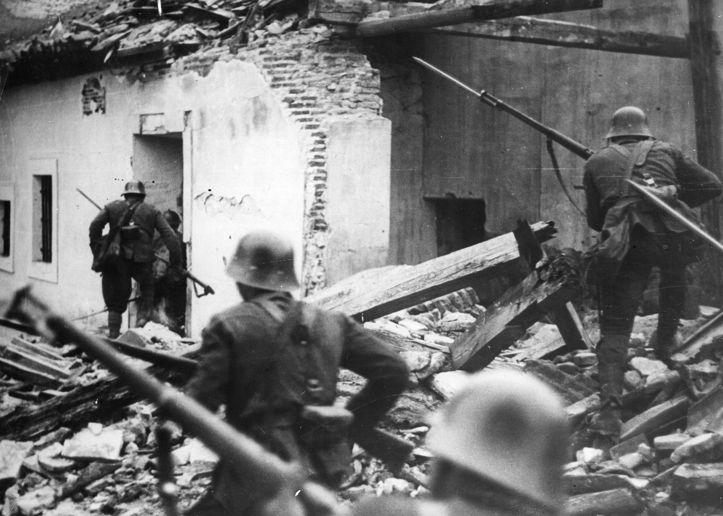Nationalist troops advance through the debris of houses wrecked in air raids in Madrid, on April 2, 1937.