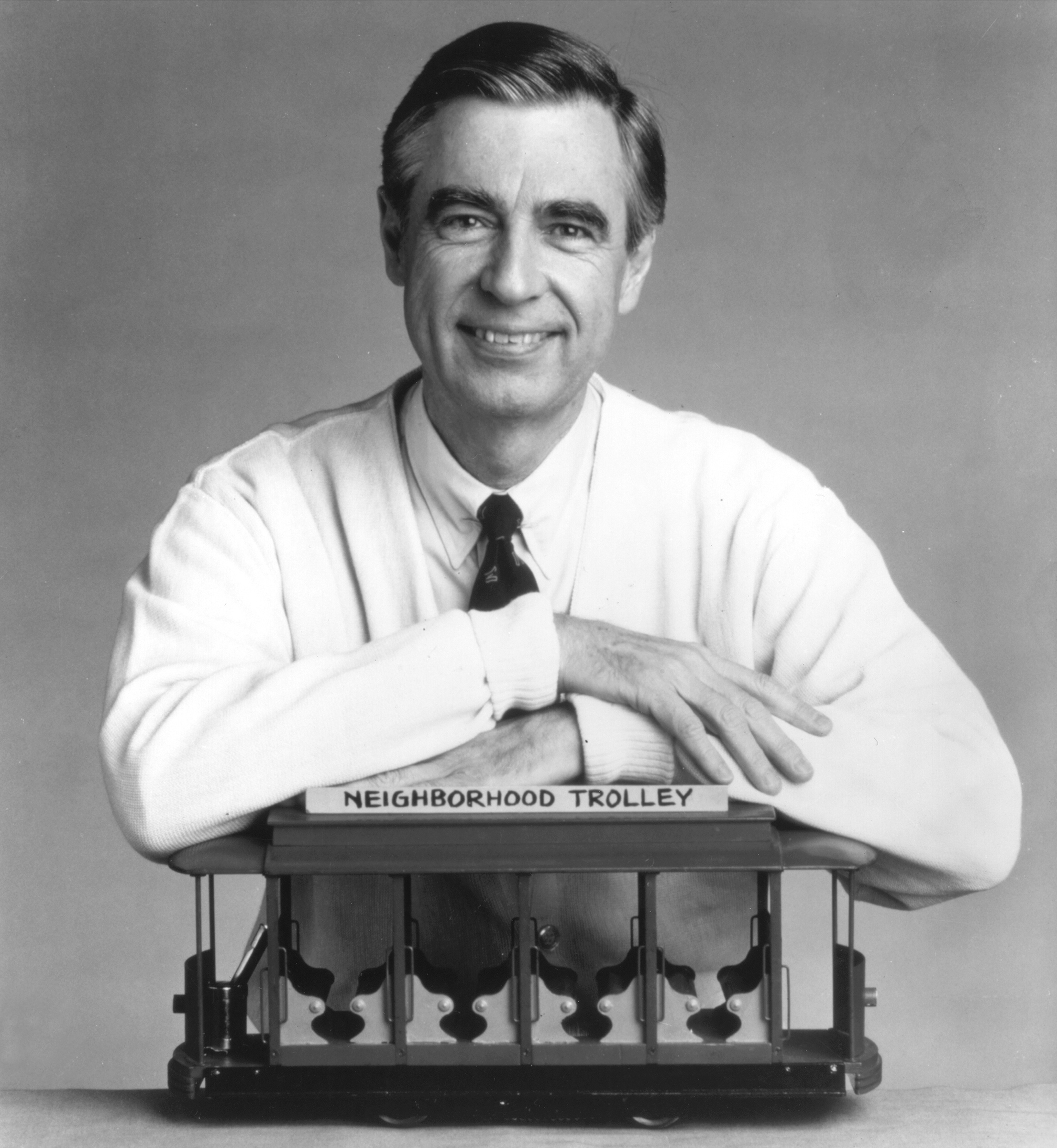 Fred Rogers, the host of the children's television series, "Mr. Rogers' Neighborhood," rests his arms on a small trolley in this promotional portrait from the 1980's.