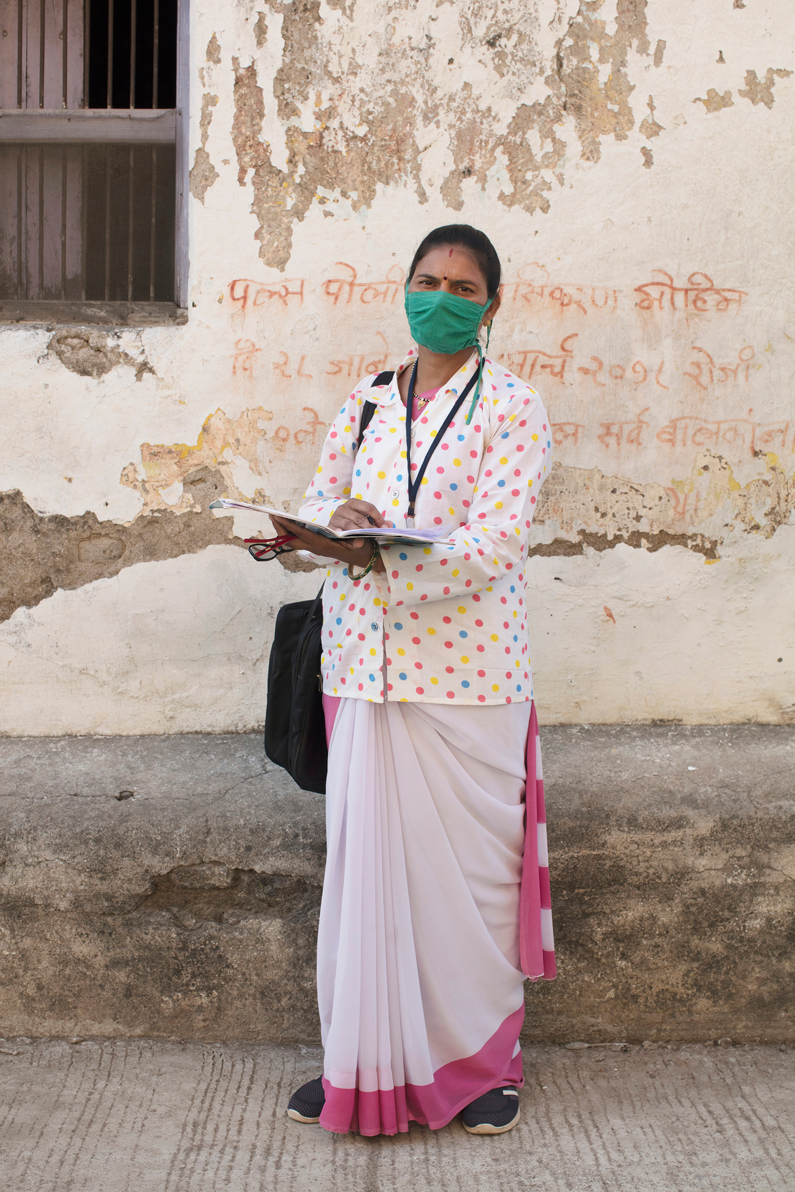 Portrait of Archana Ghugare, a community health worker, in Pavnar, Maharashtra, India, on Dec. 1, 2020. In the background is a message encouraging people to bring their children for the Polio vaccine drive.