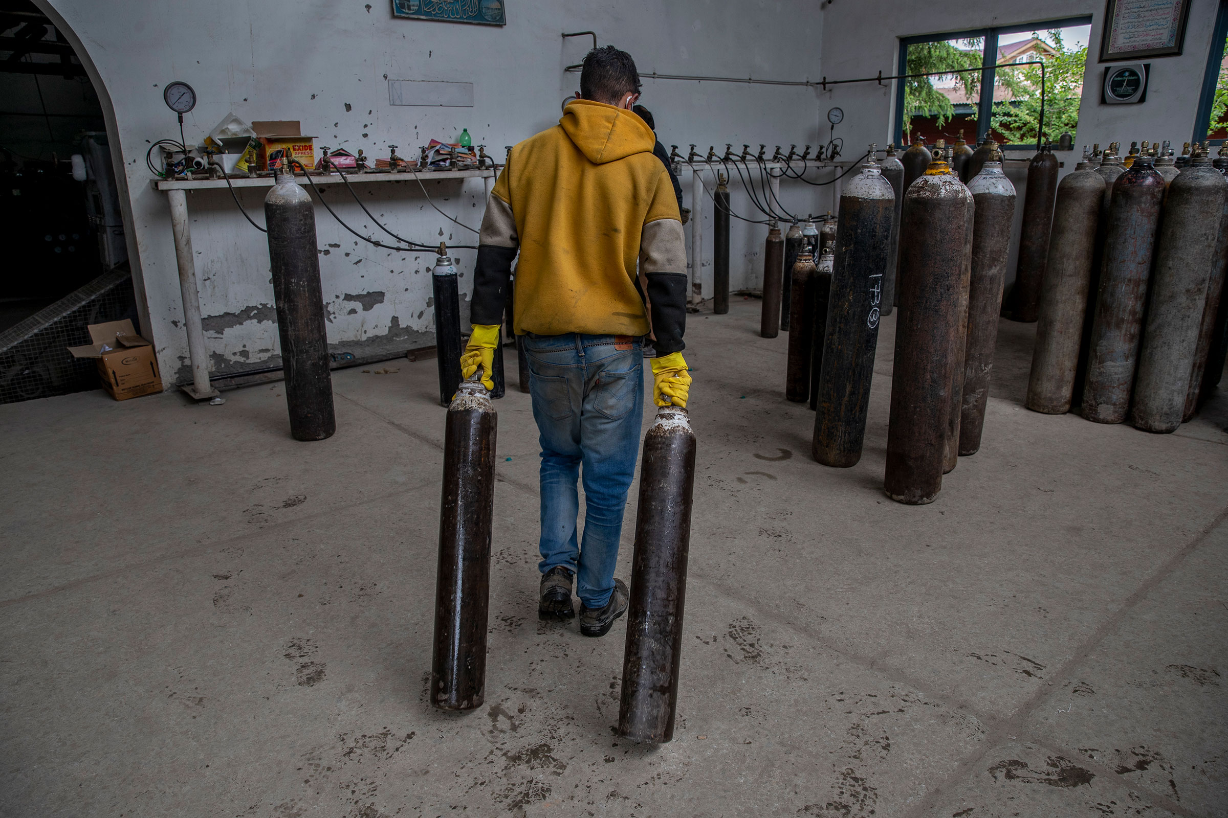 A worker moves empty oxygen cylinders for refilling at a gas supplier facility in Srinagar on May 11, 2021.