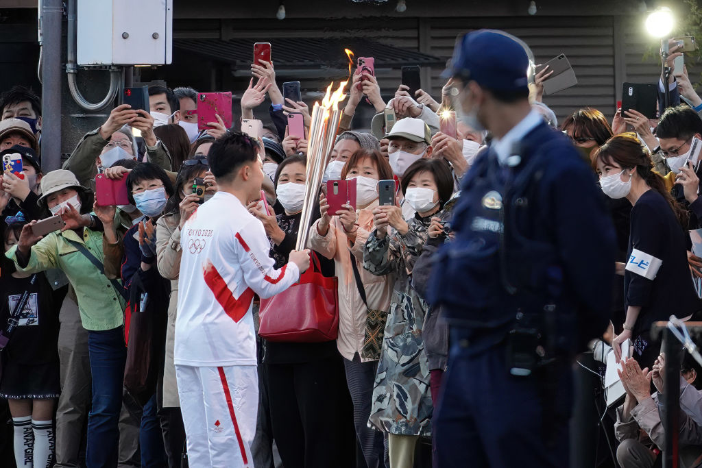 Tokyo Olympics Games Torch Relay audience seen wearing facemasks as a precaution against the spread of covid-19 take photos with their smartphones as a torch bearer shows the torch before the run on April 7, 2021. (Jinhee Lee&mdash;SOPA Images/LightRocket/Getty Images)