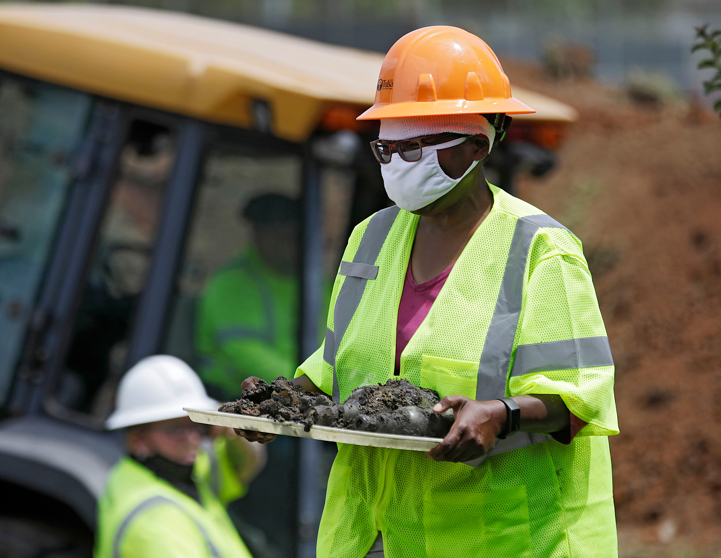 Forensic anthropologist Phoebe Stubblefield carries a tray of items found at Oaklawn Cemetery during a test excavation in the search for possible mass graves from the 1921 Tulsa Race Massacre in Tulsa, Okla on July 21, 2020.