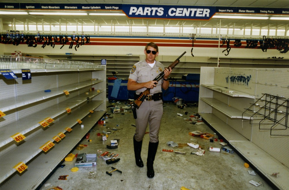 Officer Hugh Gnecco of the California Highway Patrol checks for looters in an auto parts store at Washington Boulevard and Western Avenue during the L.A. riots on May 1, 1992.