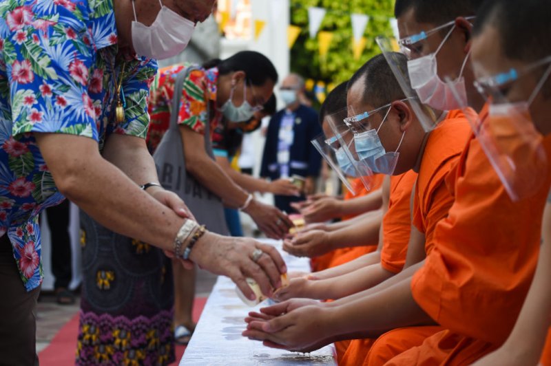 People queue to pour water on a Buddhist statue as they celebrate Songkran, also known as the Thai New Year, at Wat Pho temple in Bangkok, Thailand on 13 April 2021.