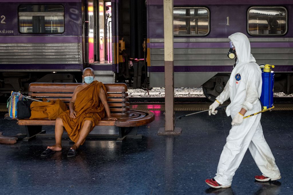 A cleaner wearing personal protective equipment (PPE) walks past a monk wearing a face mask at Hua Lamphong railway station in Bangkok on May 1, 2021, amid the latest wave of COVID-19 coronavirus cases in Thailand. (Jack Taylor&mdash;AFP /Getty Images)