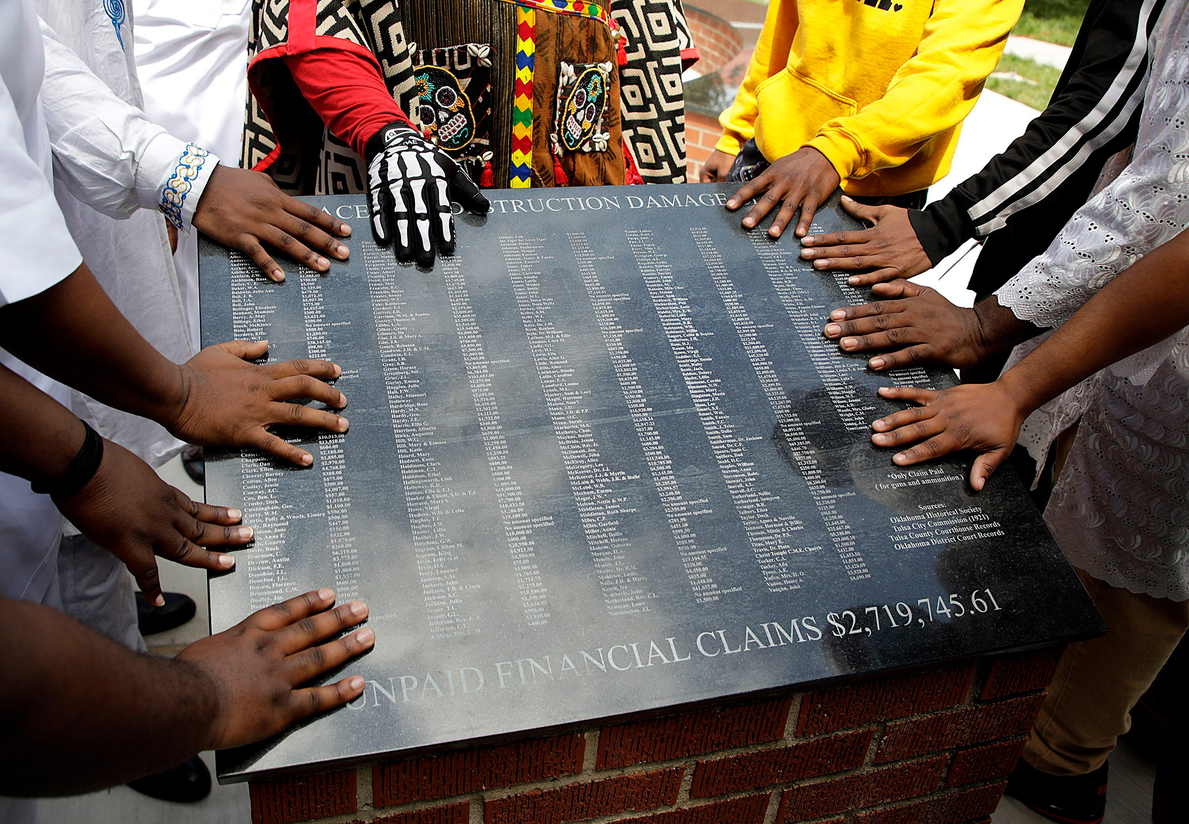 Members of the African Ancestral Society touch the 1921 Black Wall Street Memorial during the Black Wall Street Memorial March in Tulsa, Okla., on May 28, 2021.