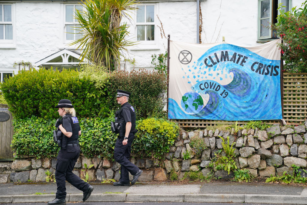 Police officers walk past a banner regarding climate change in Carbis Bay, ahead of the G7 summit in Cornwall. Picture date: Thursday June 10, 2021. (Aaron Chown—PA Wire/PA Images)