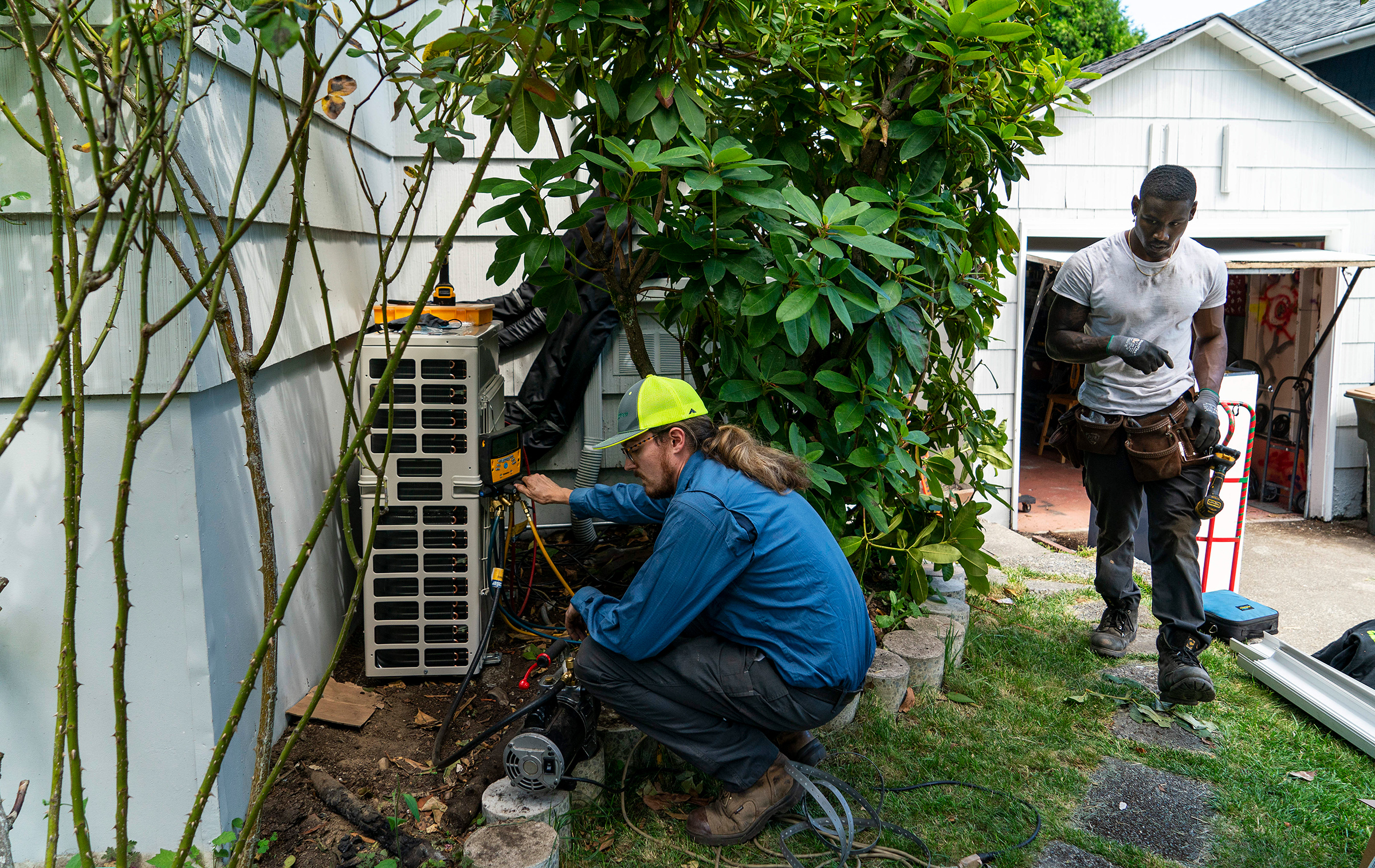 Luke Peters, left, and Elliott Thomas install a mini-split heating and air conditioning system at a home in Seattle on June 23, 2021. An intense heat wave soon set records across the region.