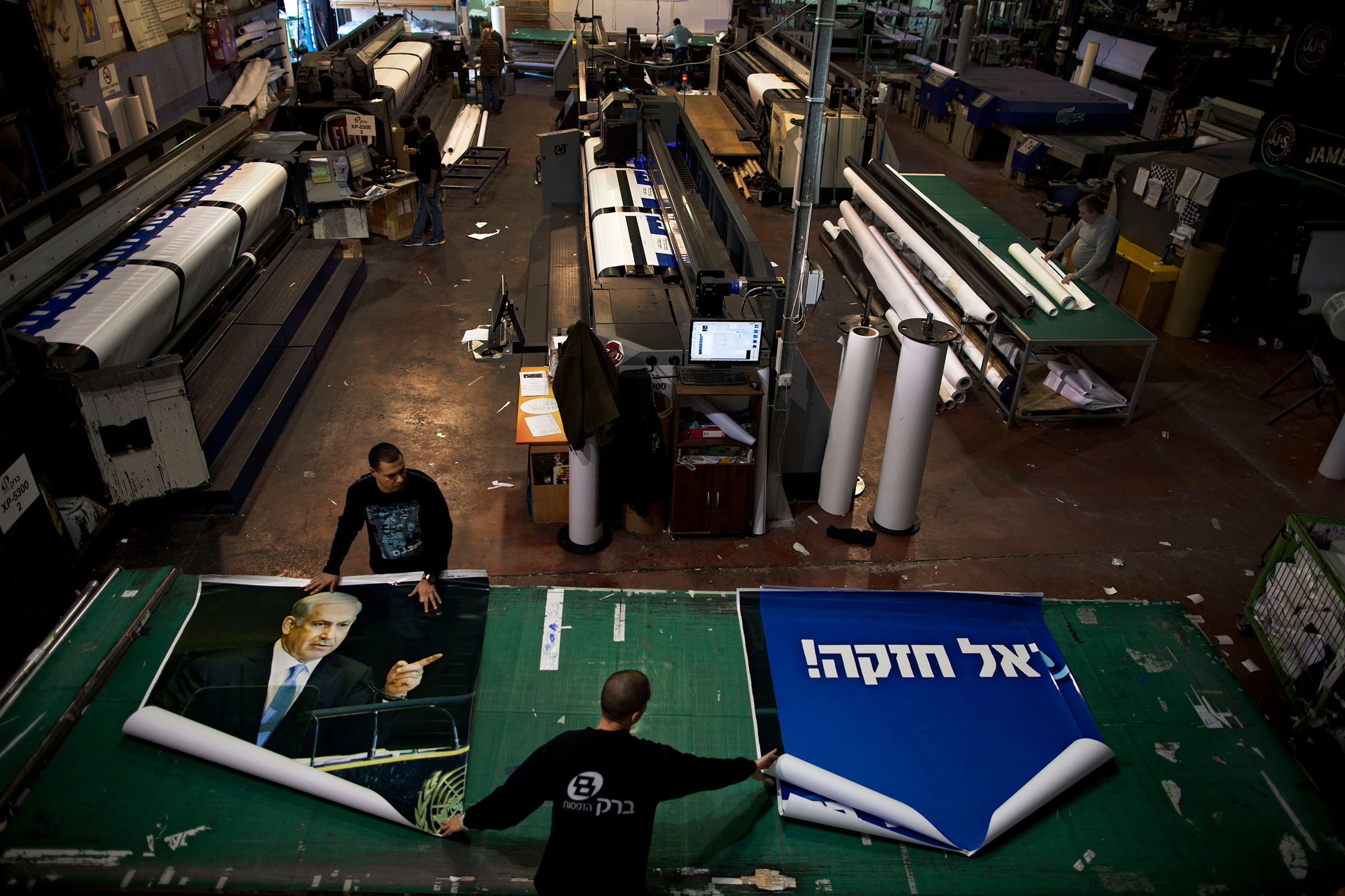 Printing house employees work on a campaign billboard for Israeli Prime Minister and Likud Party leader Benjamin Netanyahu in central Petah Tikva in 2013.