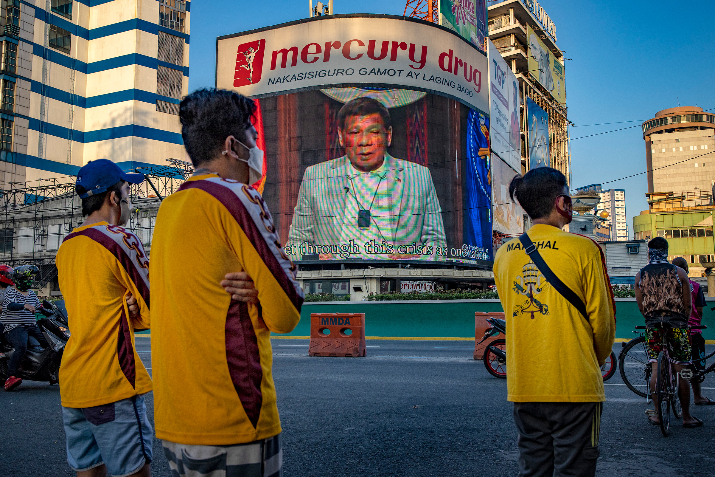 An electronic billboard displays a video of Duterte as Catholic devotees pray outside a closed church in Manila on April 2, defying government orders to avoid religious gatherings and stay home during Holy Week to curb the spread of the coronavirus. (Ezra Acayan—Getty Images)