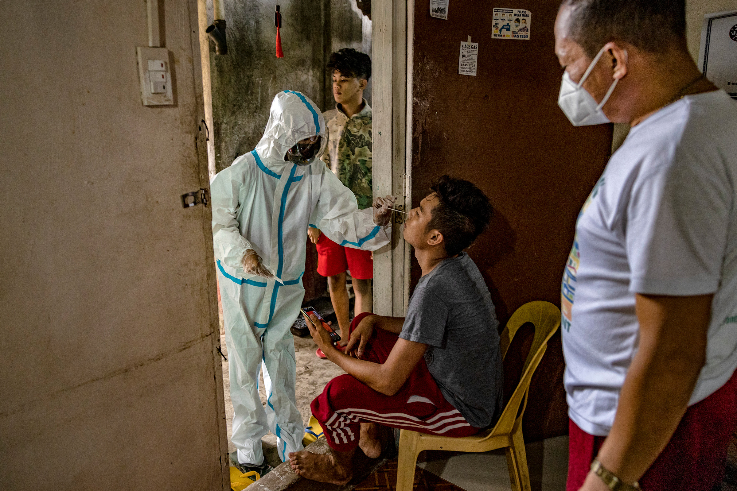 Katrina Pelotin, a field nurse from the City Epidemiology and Surveillance Unit, conducts a swab test on a family member of a COVID-19 patient isolating at home as part of contact tracing efforts in Quezon City, Metro Manila, on April 15. (Ezra Acayan—Getty Images)