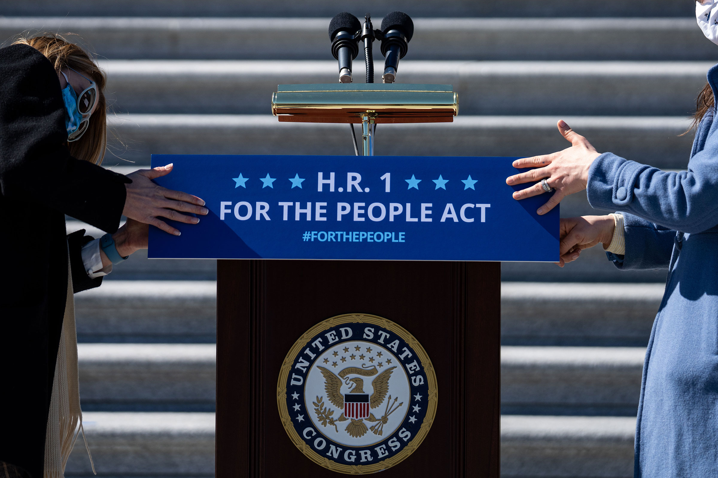 Staffers place a sign on a podium in preparation for a news conference with House Democrats regarding H.R. 1, the For the People Act, on Capitol Hill on March 3, 2021. (Kent Nishimura—Los Angeles Times/Shutterstock)