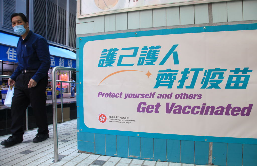 A man in a facemask walked past a COVID-19 vaccination center in Hong Kong on March 25, 2021. After a sluggish vaccination, more Hong Kong residents are finally signing up for their first shots in June. (Olivier Chouchana–Gamma-Rapho/Getty Images)