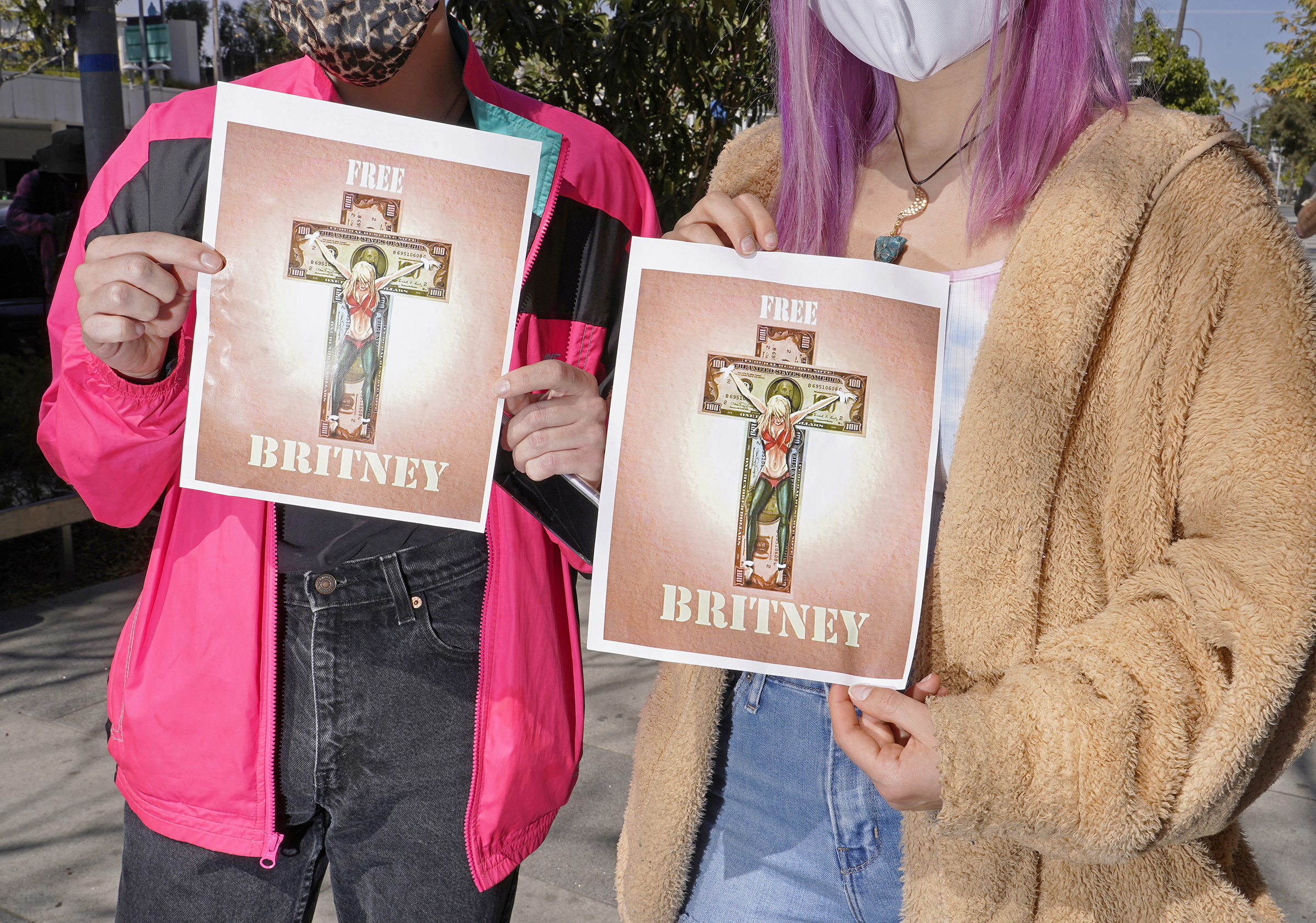 Two protesters hold signs outside a hearing related to Britney Spears' conservatorship in March 2021.