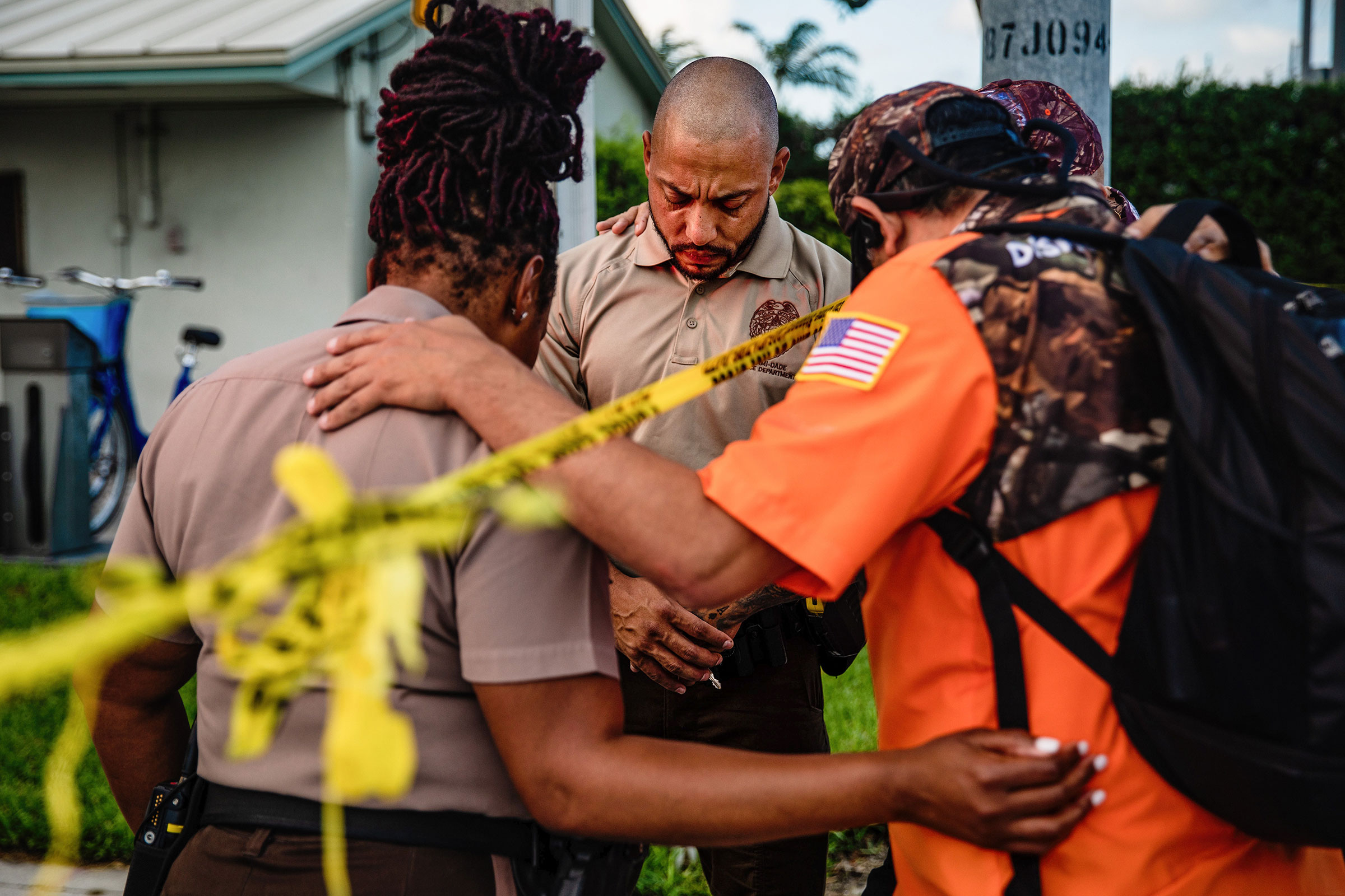 Members of a Christian mens group pray with Miami-Dade Police Department officers outside the Champlain Towers South collapse site on June 26. (Scott McIntyre—The New York Times/Redux)