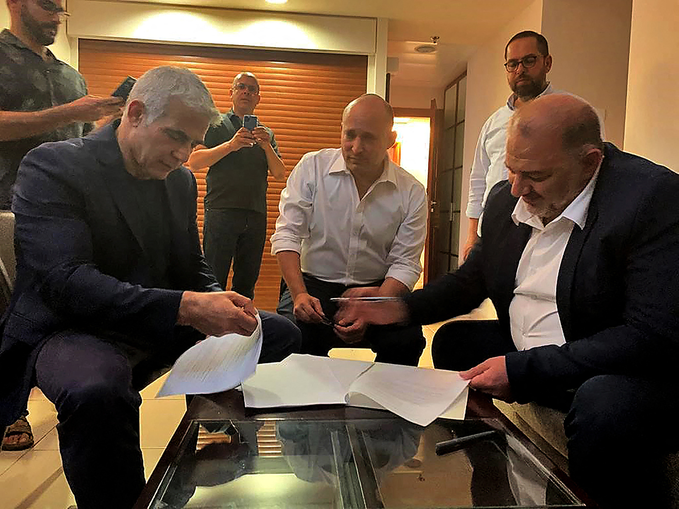 A handout picture provided by the United Arab List on June 2, 2021, shows Mansour Abbas, right, signing a coalition agreement with Israel's opposition leader Yair Lapid, left, and right-wing nationalist Naftali Bennett in Ramat Gan near the coastal city of Tel Aviv. (United Arab List/AFP/Getty Images)