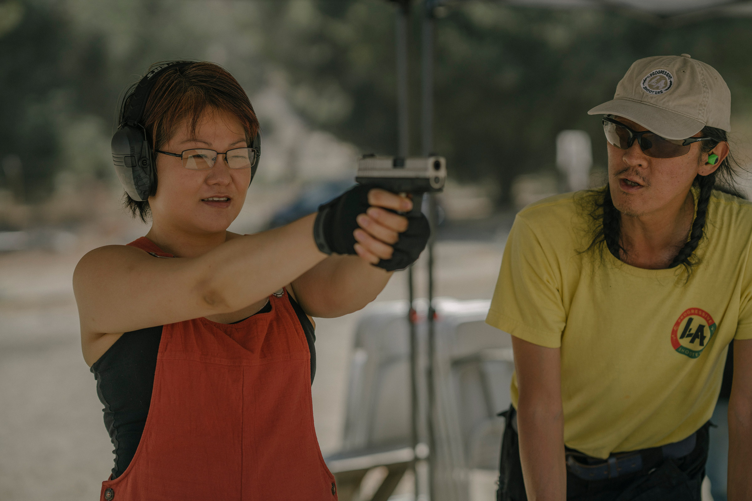 Svetlana Kim practices shooting her new handgun while standing next to Tom Nguyen, instructor and founder of L.A. Progressive Shooters, at the Burro Canyon Shooting Park in Azusa, CA on July 18, 2020.  Nguyen founded L.A. Progressive Shooters in the hopes of diversifying the population of gun owners. (Isadora Kosofsky for TIME)