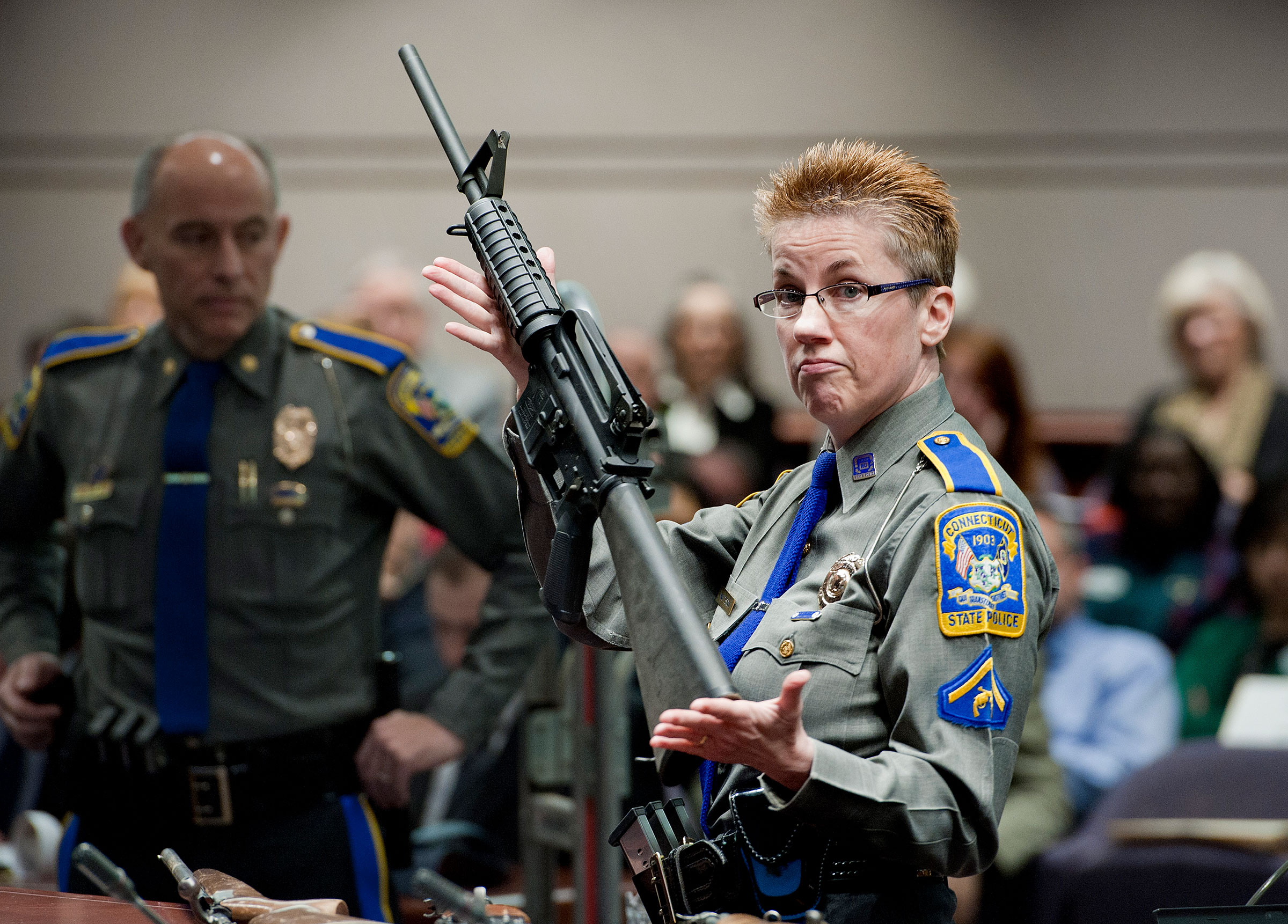 Firearms Training Unit Detective Barbara J. Mattson of the Connecticut State Police holds up a Bushmaster AR-15 rifle, the make and model of gun used in the 2012 Sandy Hook shooting, for a demonstration during a hearing of a legislative subcommittee reviewing gun laws, in Hartford, Conn., on Jan. 28, 2013. (Jessica Hill/AP)