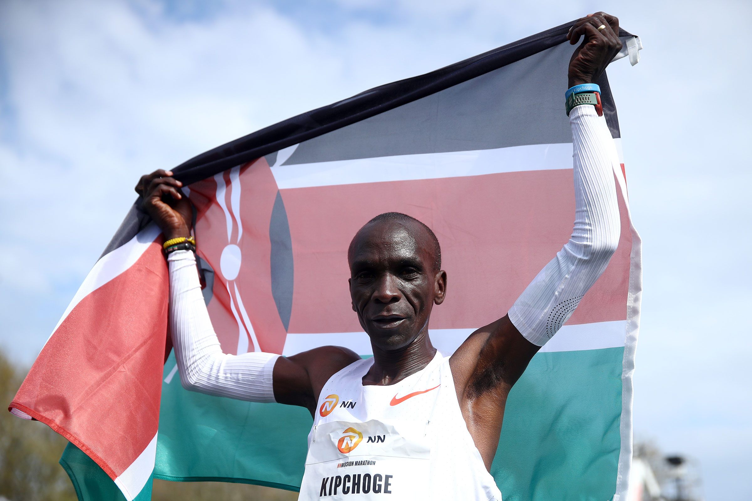 Eliud Kipchoge of Kenya, winner of the gold medal, crosses the finishing line and celebrates with a flag during the NN Mission Marathon held on April 18, 2021 in Enschede, Netherlands.