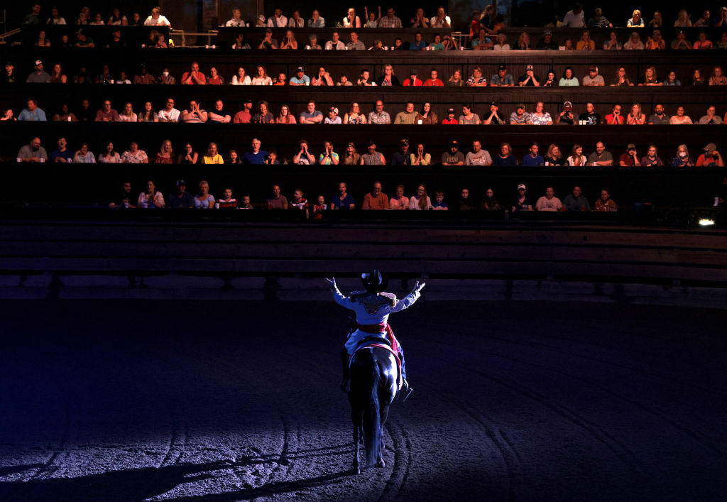 A performer spreads his arms out to those seated in The South as he divides the room of diners at Dolly Parton's Stampede into factions of North and South which will cheer on their teams as they compete in various events like barrel riding, chicken chasing, and pig races in Branson, MO on July 17, 2021.