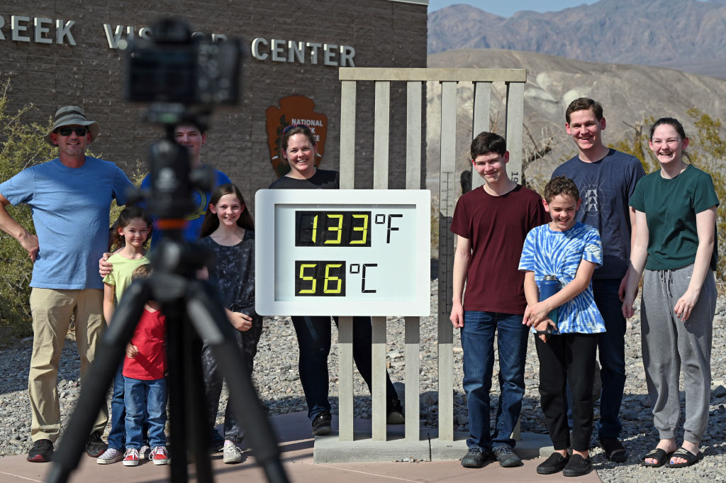 People visit the unofficial thermometer reading 133 degrees Fahrenheit/56 degrees Celsius at Furnace Creek Visitor Center on July 11, 2021 in Death Valley National Park, California.