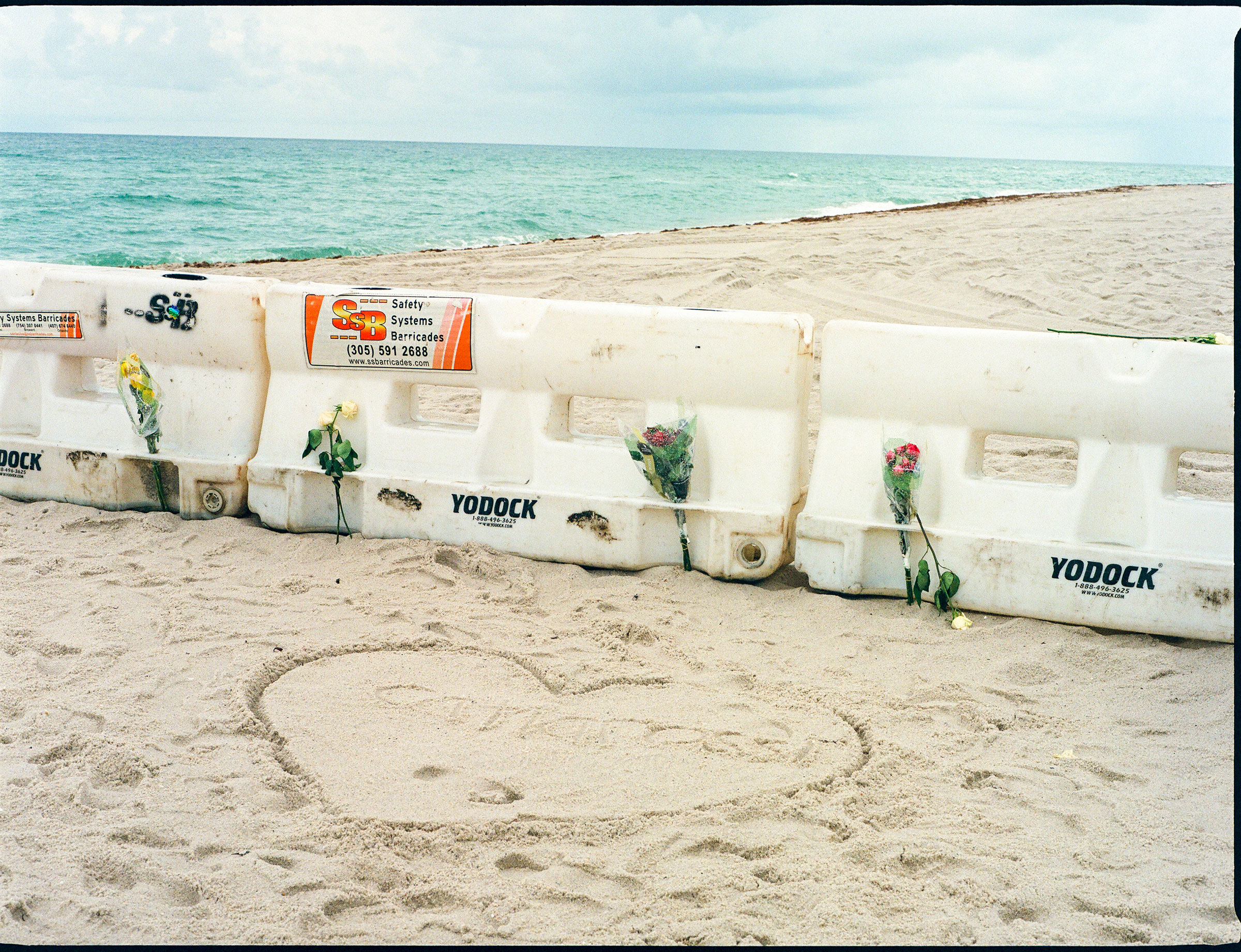 Flowers attached to barriers on the beach near where the Champlain Towers South collapsed. (Ysa Pérez for TIME)