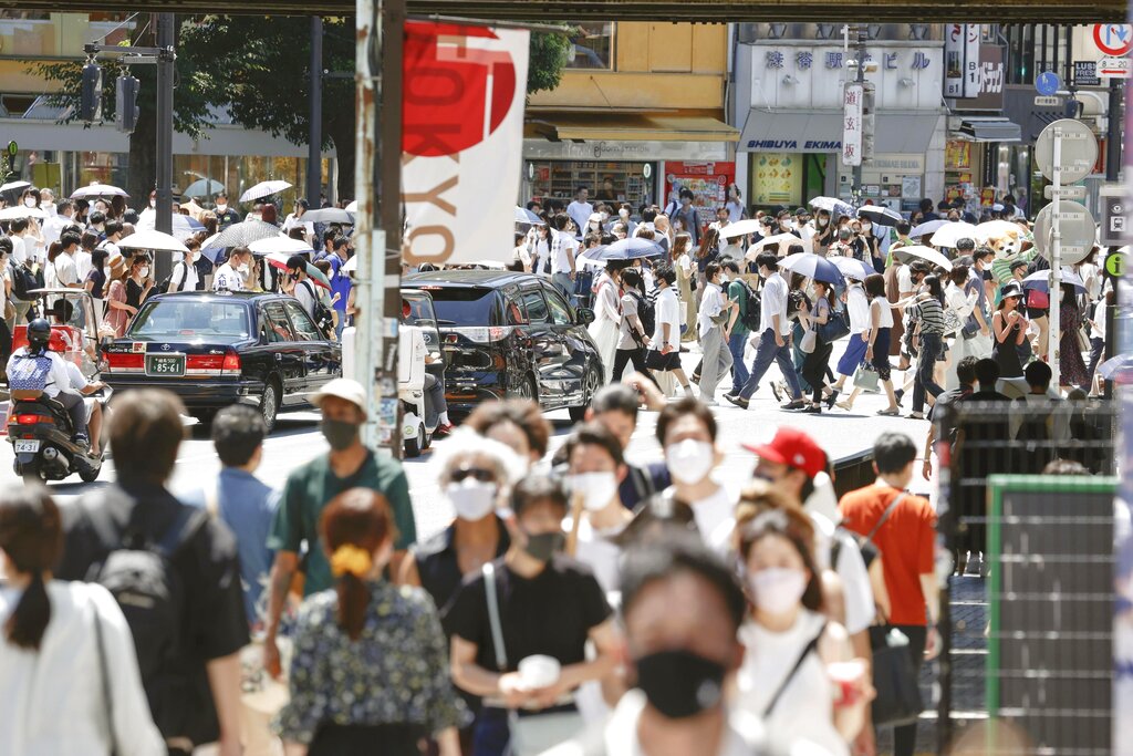 People wearing masks amid the novel coronavirus pandemic walk in Tokyo's Shibuya district on July 22, 2021, a day before the opening ceremony of the Tokyo Olympics. (Kyodo News/AP Images)