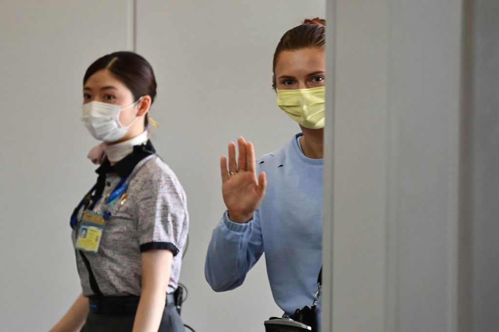 Belarus athlete Krystsina Tsimanouskaya waves goodbye as she boards a flight at Narita International Airport outside Tokyo on Aug. 4, 2021, after traveling from the Polish embassy, where she had spent the past two nights following claims her team tried to force her to return home after she criticized her coaches during the Tokyo Olympic Games. (Charly Triballeau–AFP/Getty Images)