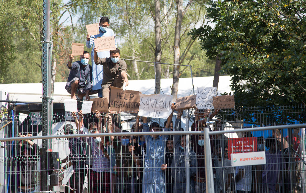 Migrants at a camp in Rudninkai in Lithuania hold up placards with inscriptions such as "Help Afghanistan" and similar demands during a rally on Aug.16, 2021 (Alexander Welscher—dpa/picture alliance via Getty Images)