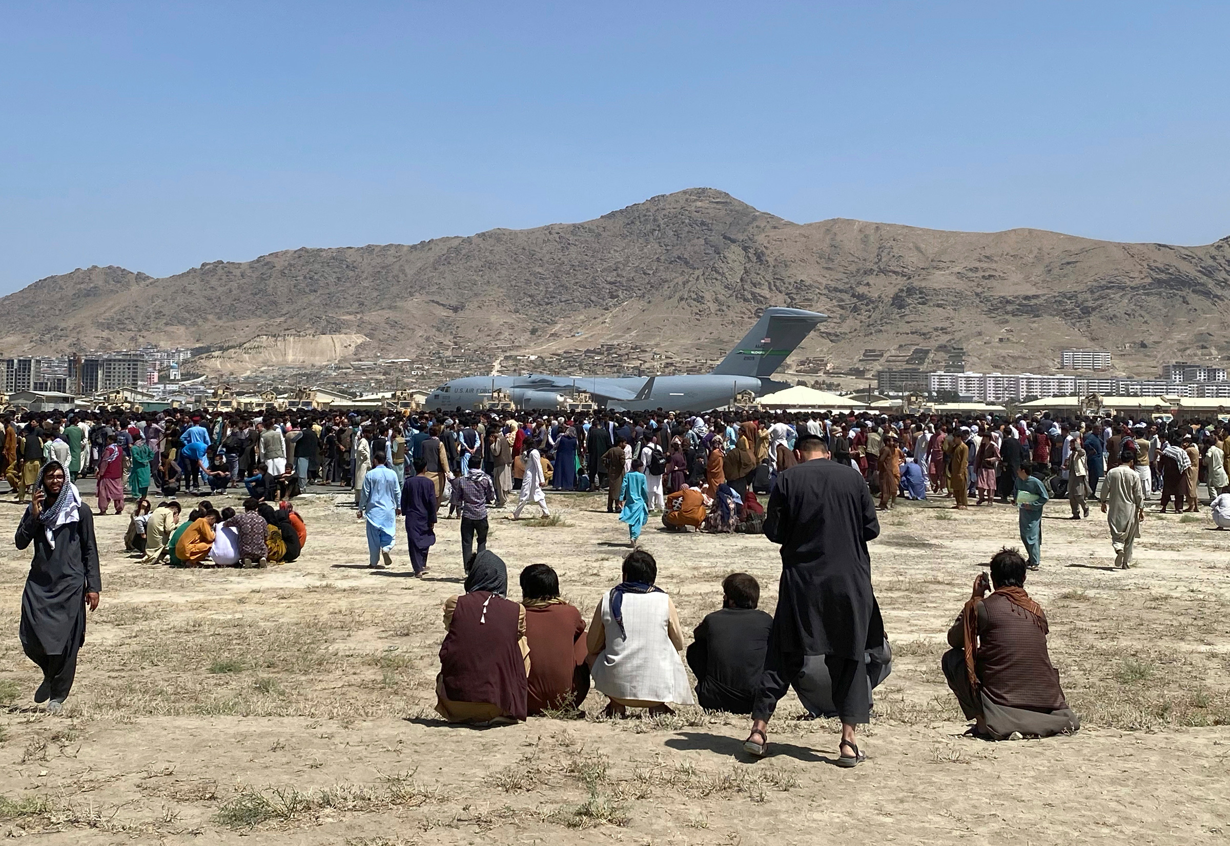 Hundreds of people gather near a U.S. Air Force C-17 transport plane at a perimeter at the international airport in Kabul on Monday, Aug. 16.