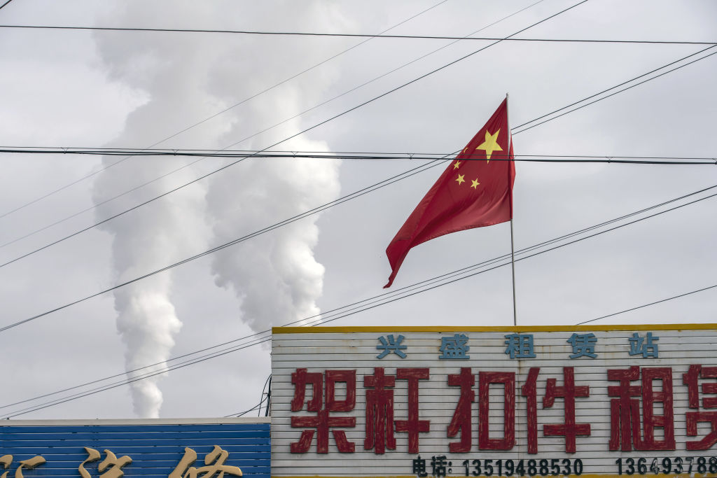 The Chinese flag flies in front of exhaust rising from a coal fired power plant in Jiayuguan, Gansu province, China, on April 1, 2021. (Qilai Shen/&mdash;Bloomberg/Getty Images)