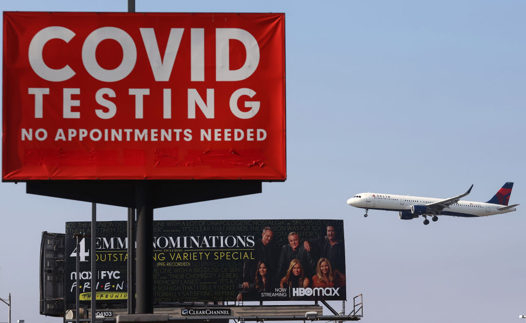 A Delta Air Lines plane lands near a COVID-19 testing sign at Los Angeles International Airport on Aug. 25, 2021. (Mario Tama—Getty Images)