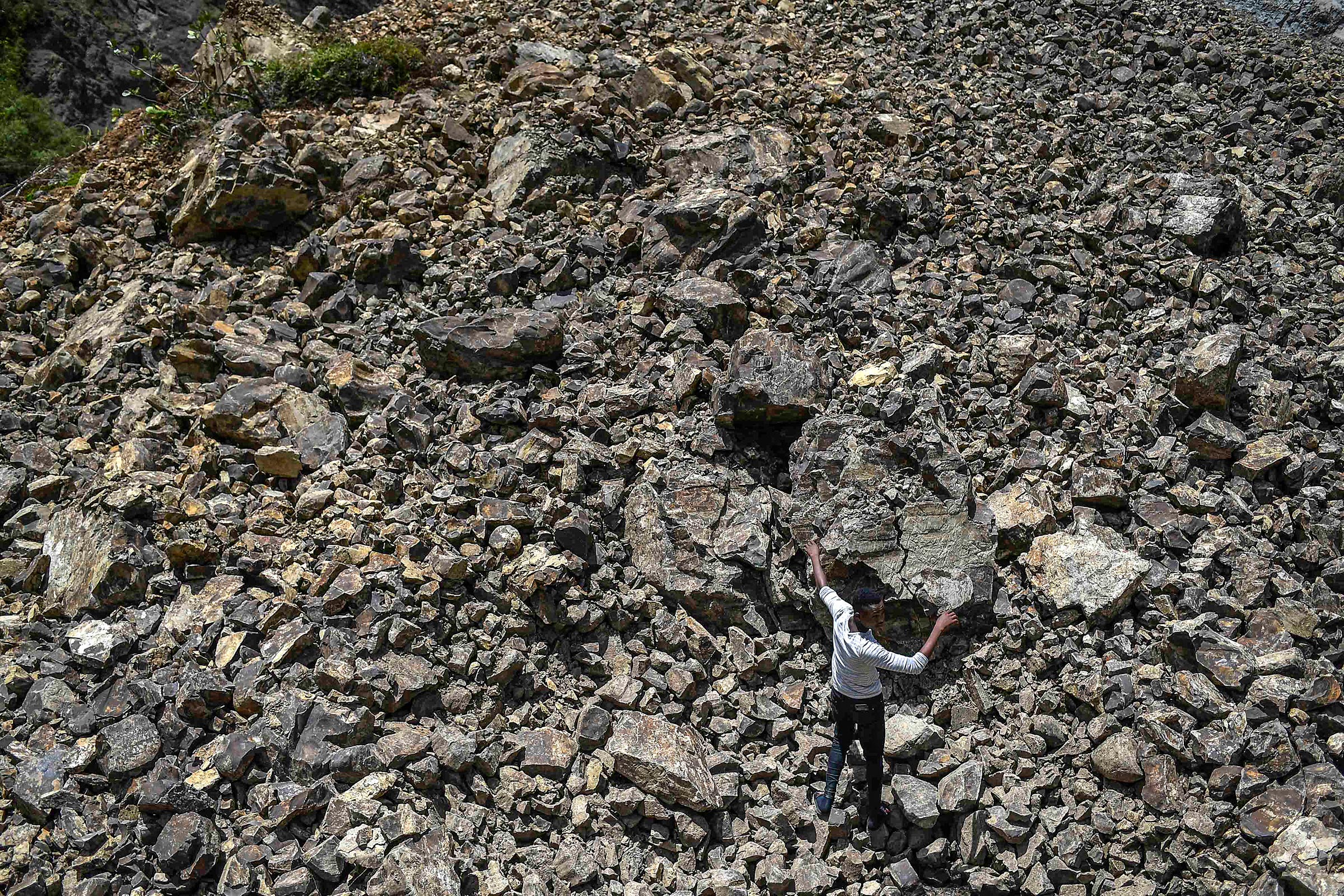 A man walks over rubble that covered a road during a landslide triggered by the earthquake in River Glass on Aug. 18.